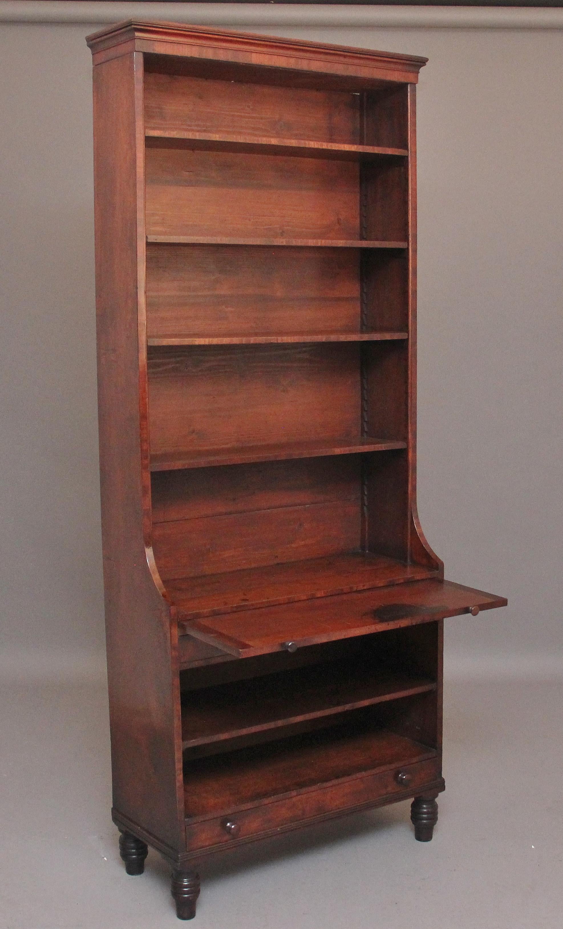 A narrow early 19th century mahogany open bookcase, consisting of four adjustable shelves on the top section, brushing slide below and two drawers with a fixed shelf in between, the slide and drawers having the original turned wooden knob handles,