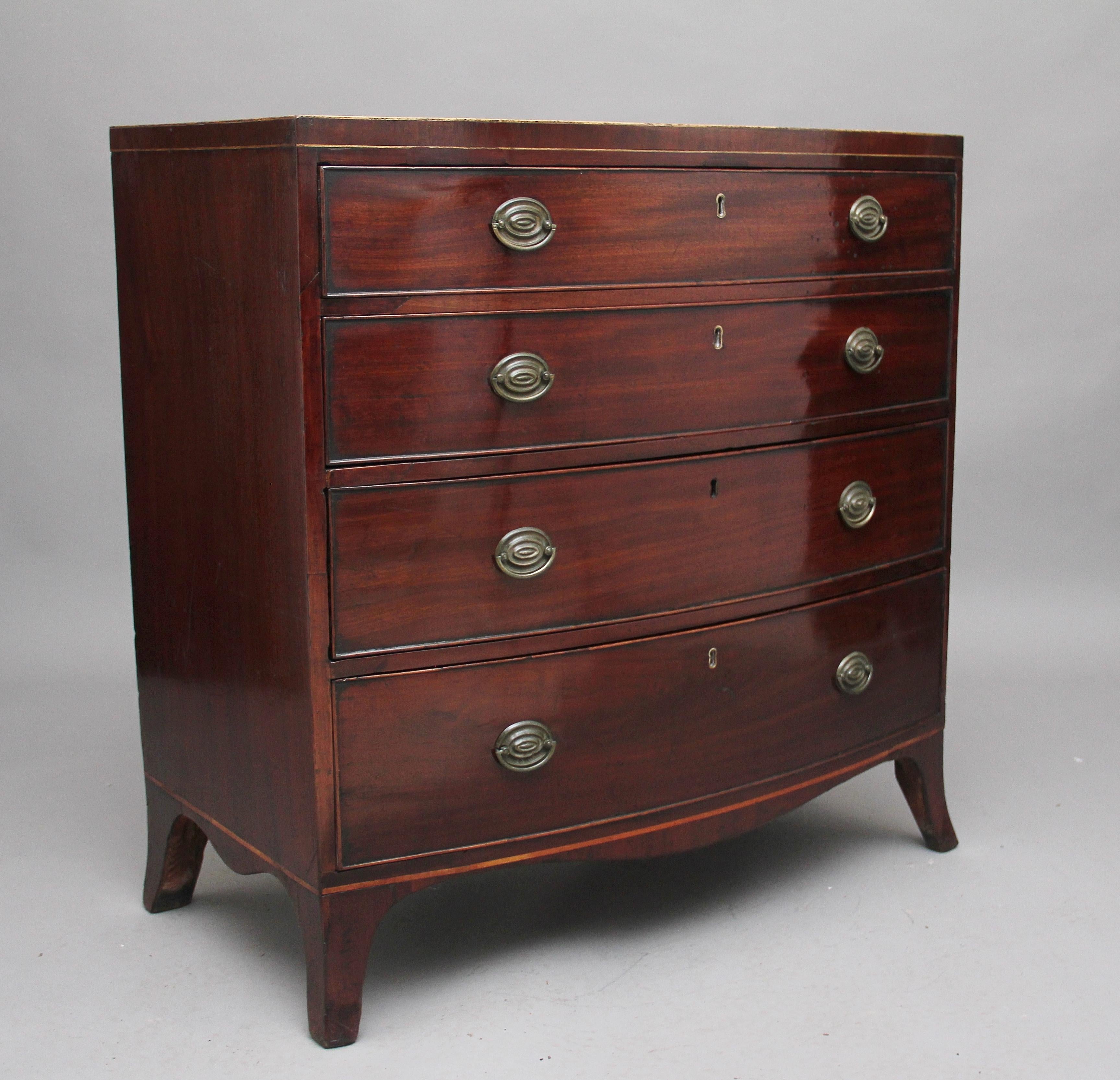 Early 19th century mahogany bowfront chest of drawers, the crossbanded top decorated with white line inlay above four long graduated drawers with original brass plate handles, having a shaped apron and standing on splay feet, circa 1800.