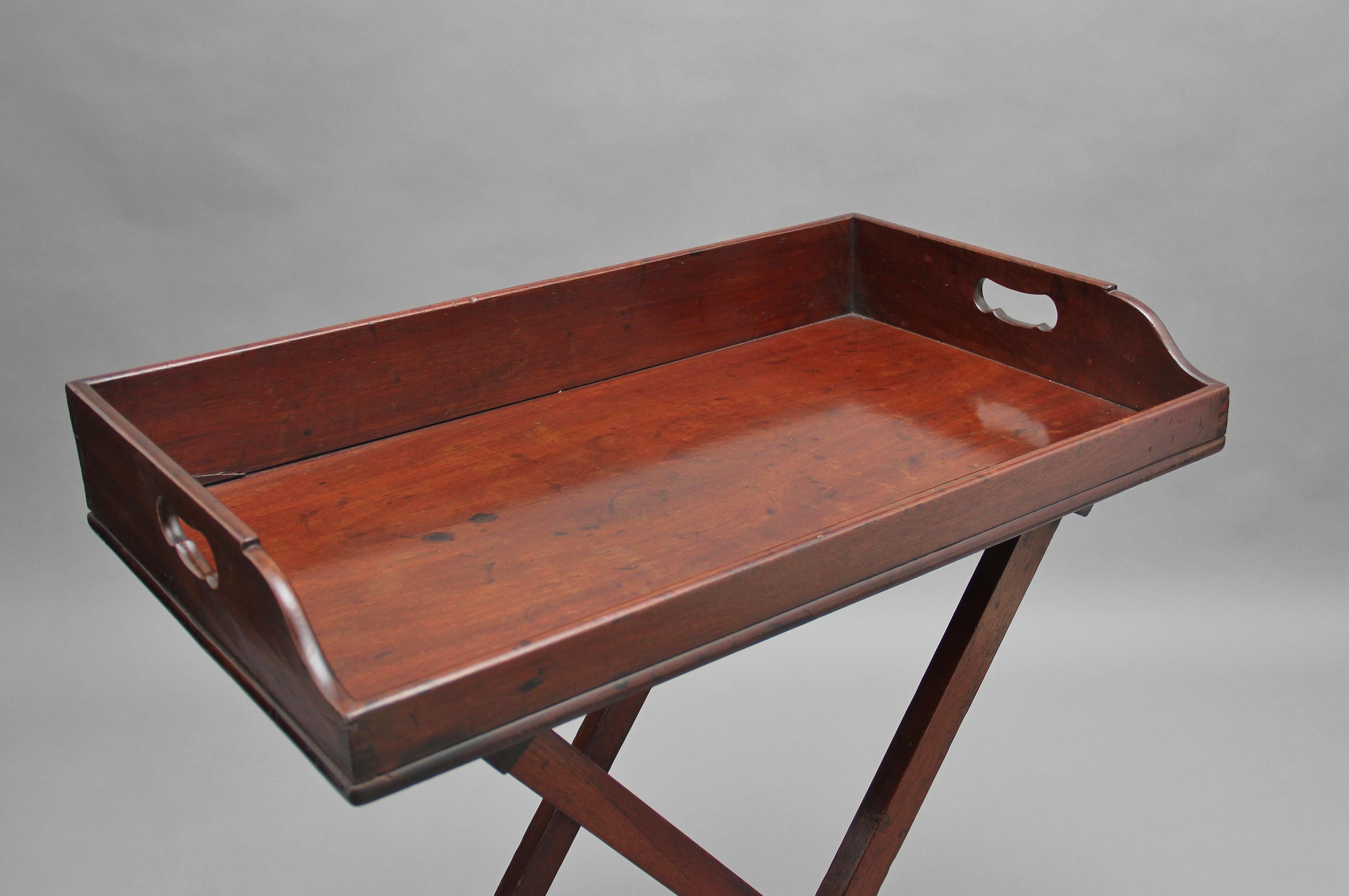 A lovely quality 19th century mahogany butlers tray on stand, the rectangular shaped tray with a surround gallery three quarters raised and with two fret cut carrying handles above a folding stand, circa 1830.
 