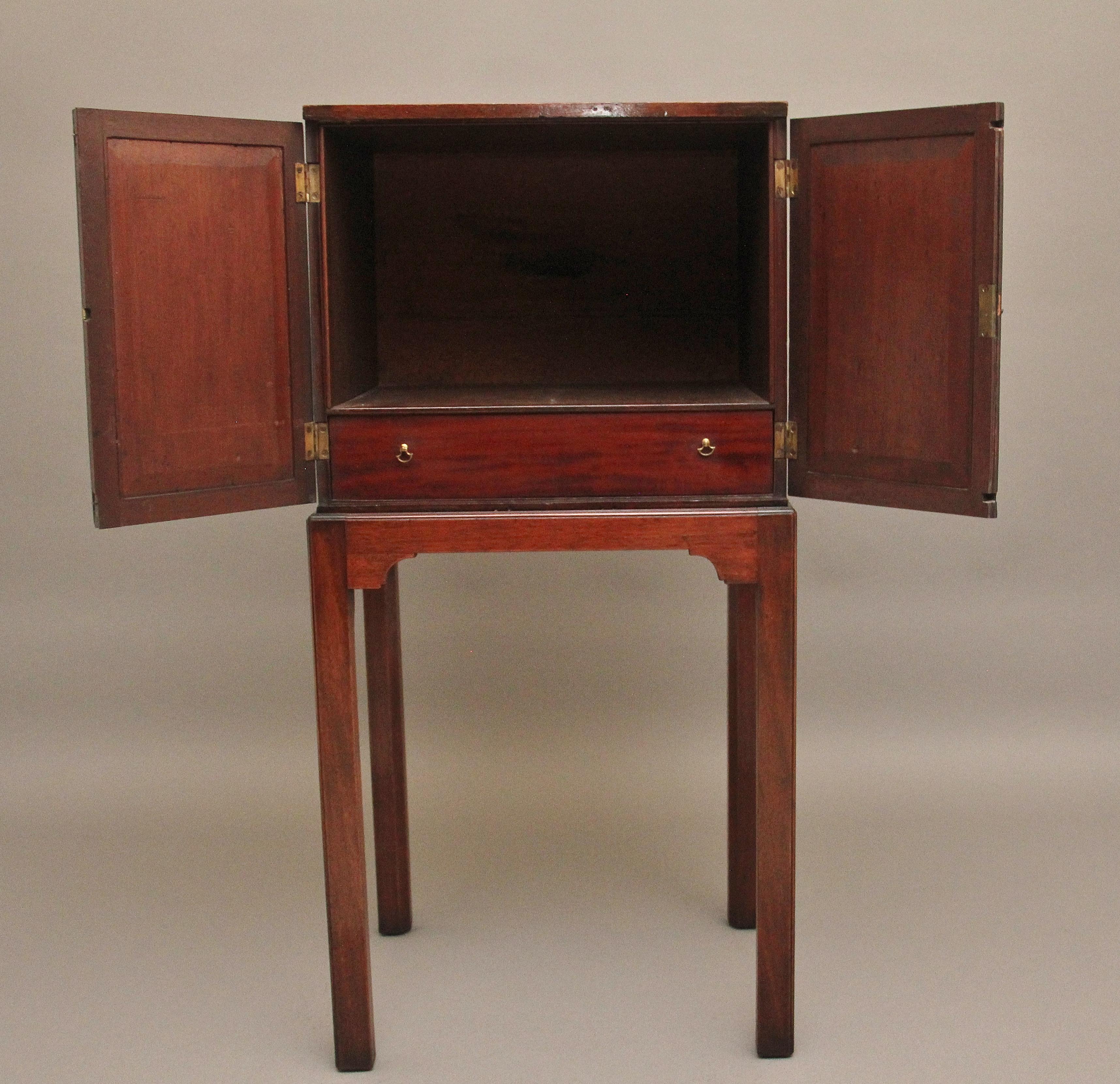 Early 19th Century mahogany cabinet on stand, having two hinged doors with decorative shaped panels that have wonderful figuration, opening to reveal a large compartment space and a single oak lined drawer at the bottom, supported on a stand with a