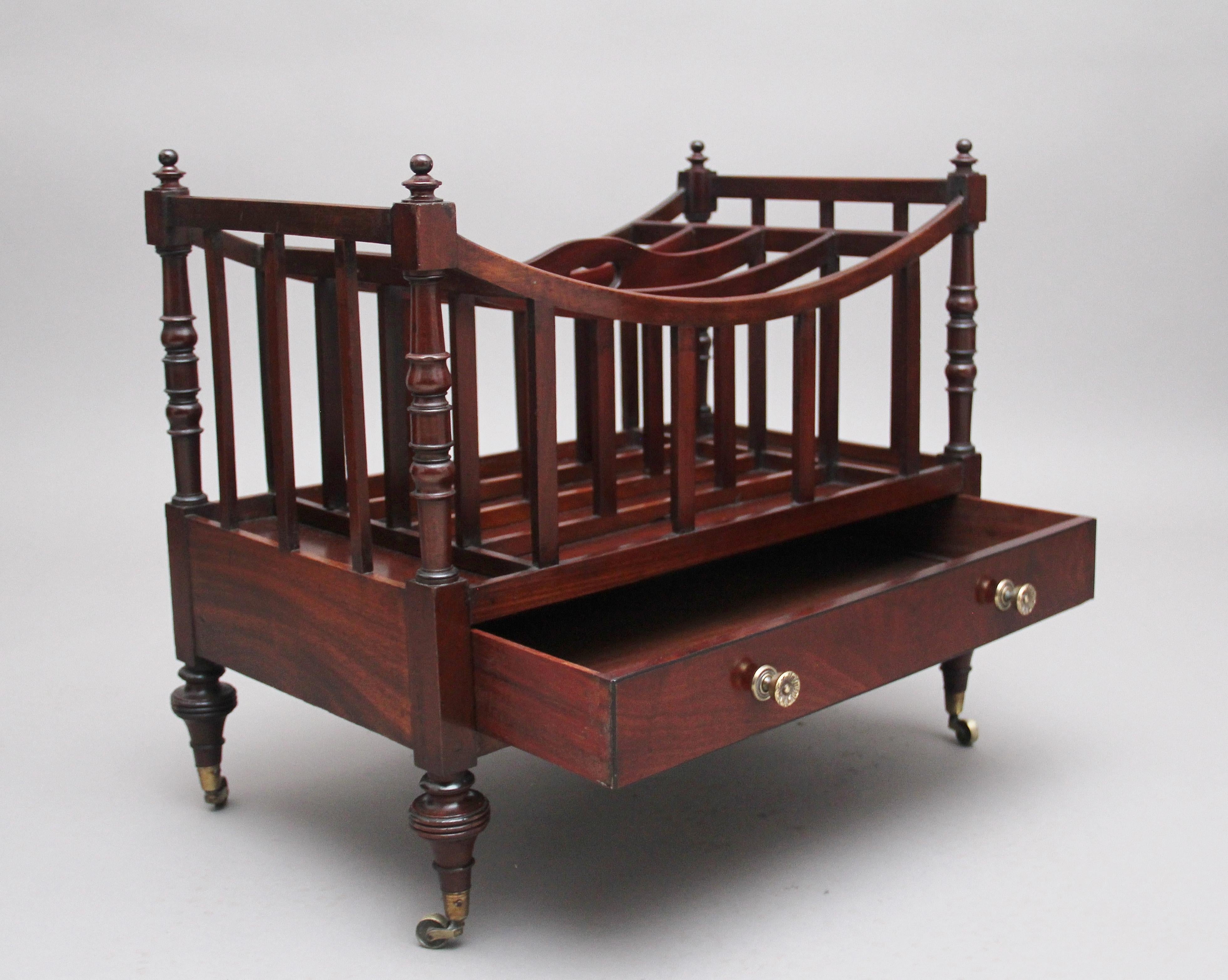 Early 19th century mahogany canterbury, the curved top having turned columns in each corner finished with turned finials, inside having three dividers, having a mahogany lined frieze drawer below with original brass turned knobs, supported on turned