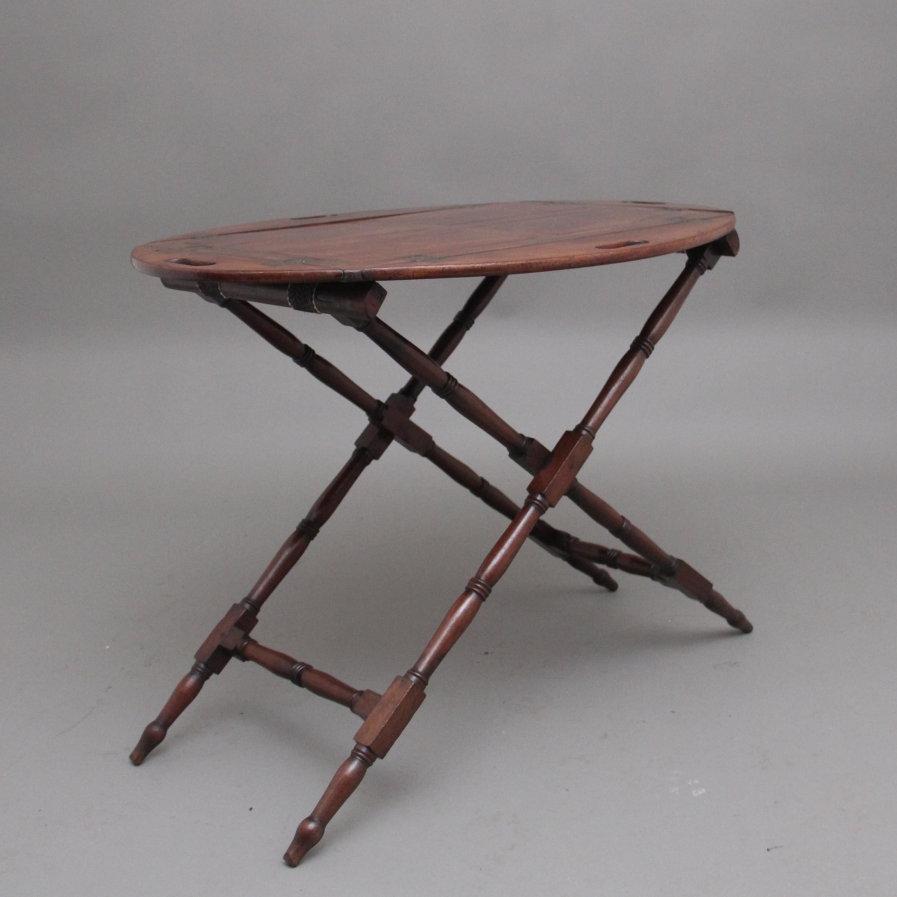 Early 19th Century mahogany folding butlers tray on stand, the rectangular paneled tray has four folding sides with inset brass hinges with each side having fret cut carrying handles, supported on folding stand with decorative turned supports. 