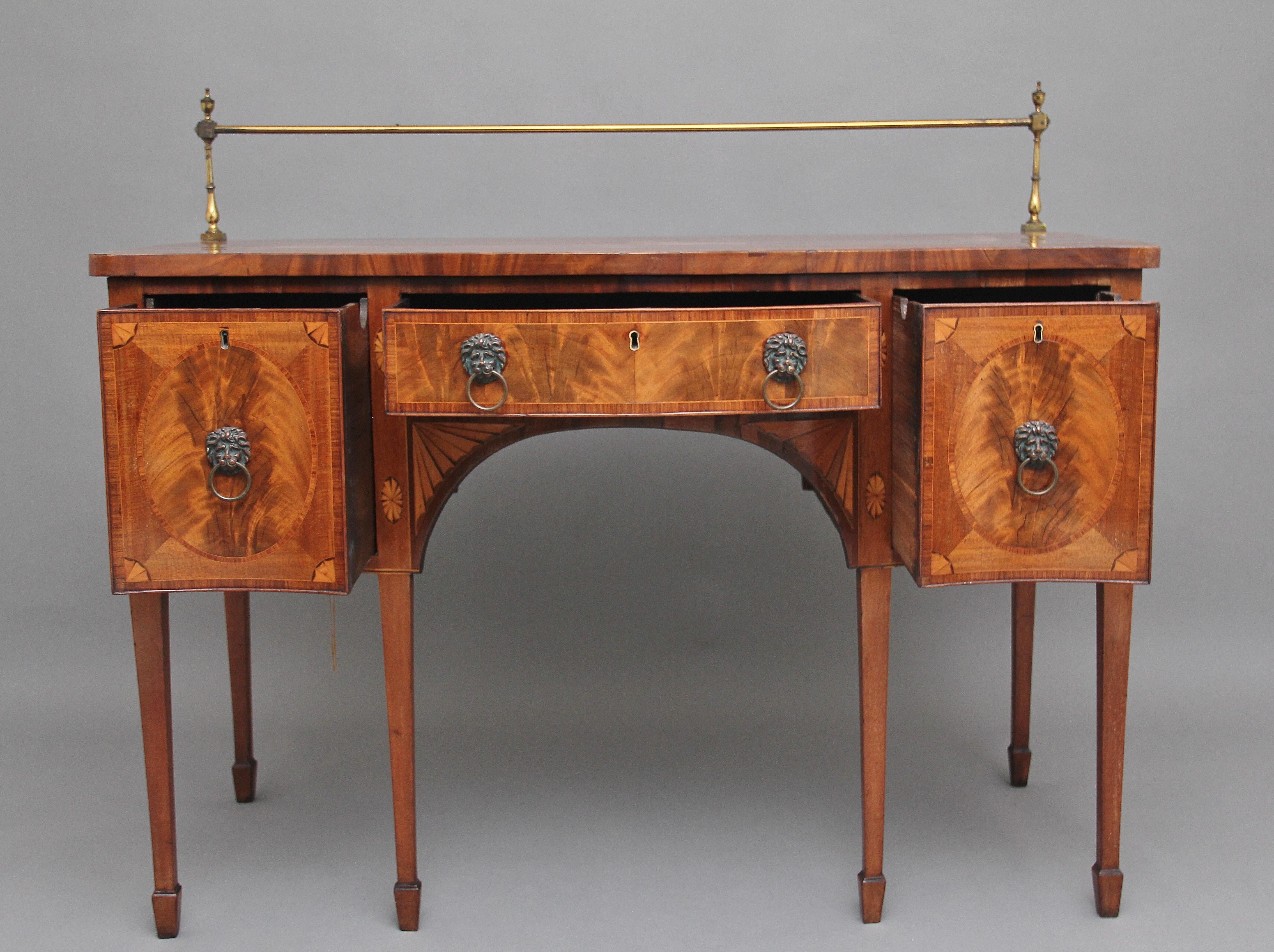 A superb quality early 19th century mahogany inlaid serpentine sideboard, having a crossbanded top with a brass gallery at the back, having a central drawer and two deep drawers either side, all drawers are oak lined and have the original lion mask