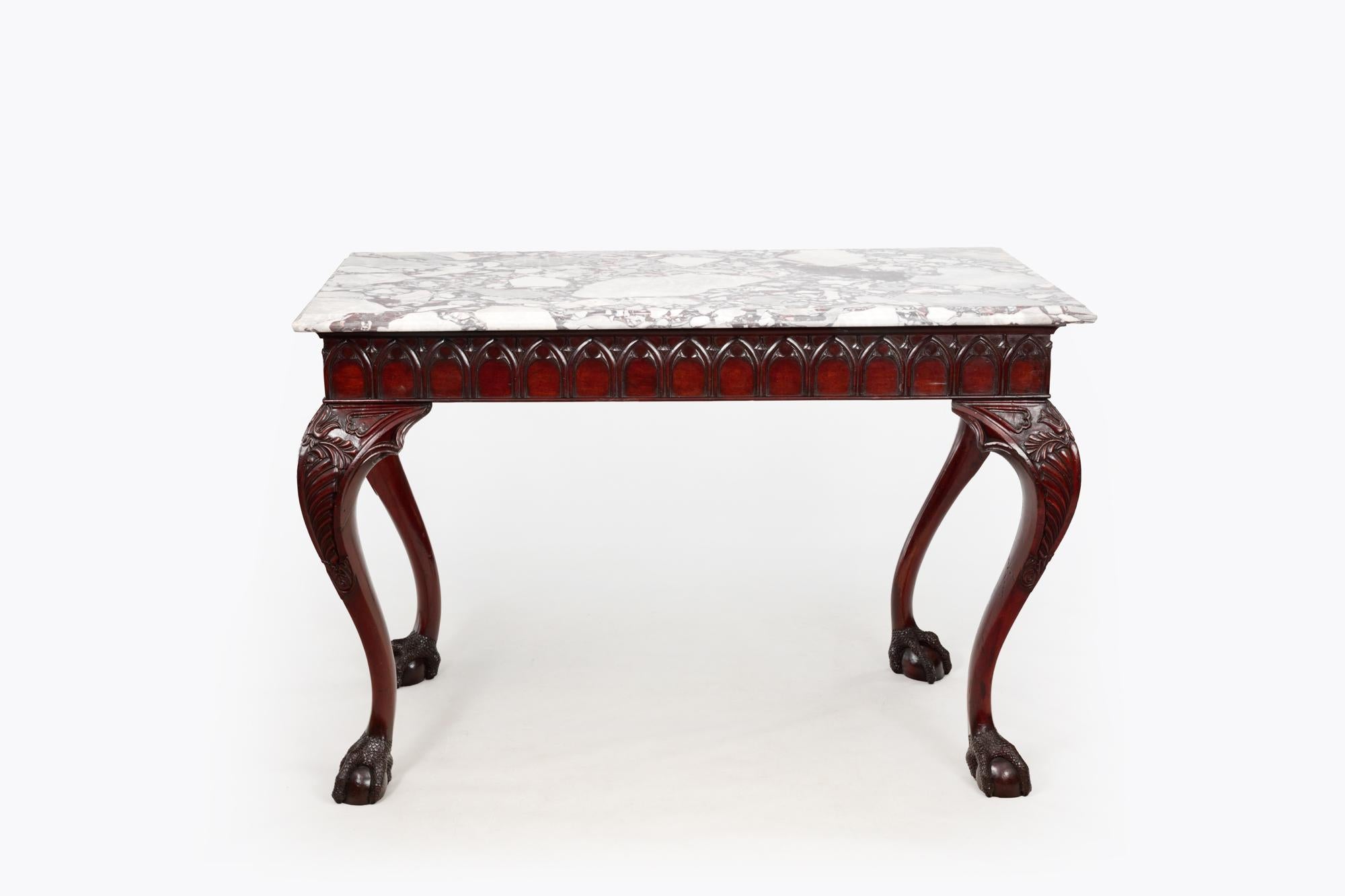Early 19th Century mahogany Irish side table with marble top. The blind fretwork frieze with arch-style carvings wraps all four sides of the tabletop which is completed by a solid rectangular marble top. This piece stands on four highly carved