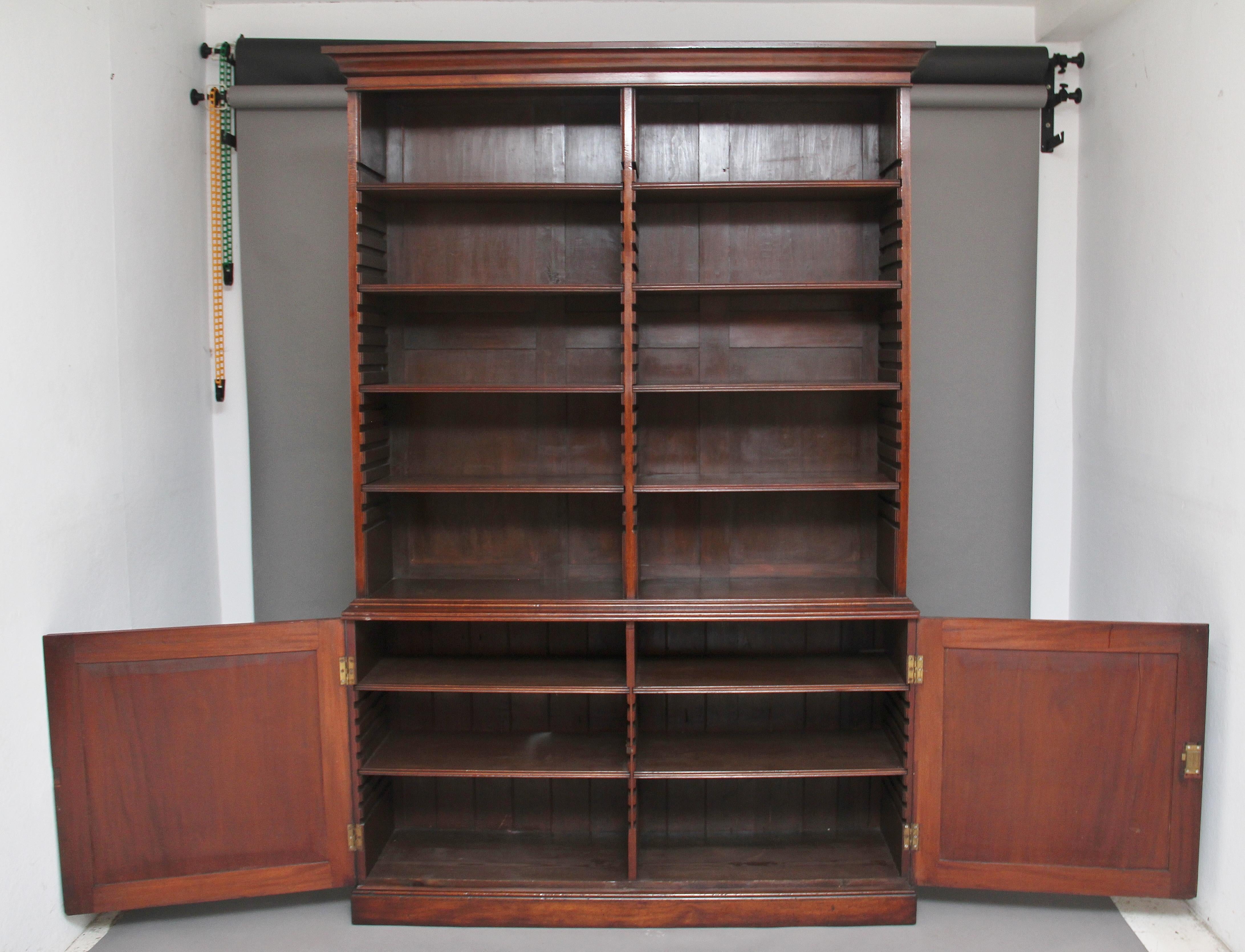 A large early 19th century mahogany open bookcase, the top section having a cornice above the bookcase divided into two sections, with each section having four adjustable shelves, the cupboard has two panelled doors with double D-moulding at the top