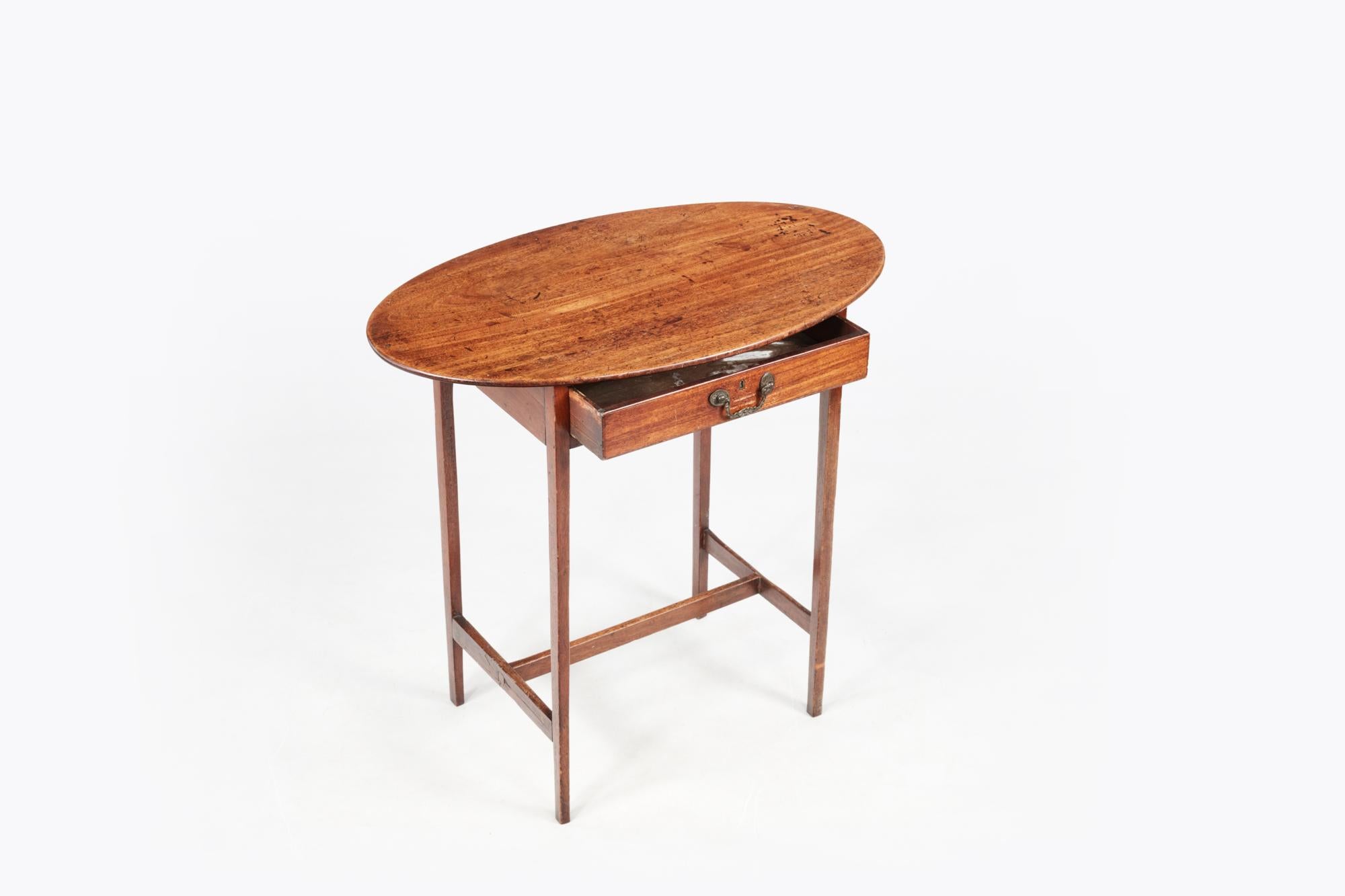 Early 19th century mahogany oval-topped occasional table, complete with single drawer featuring brass lock and swan neck handle, sitting above gently tapered legs supported by a simple stretcher.