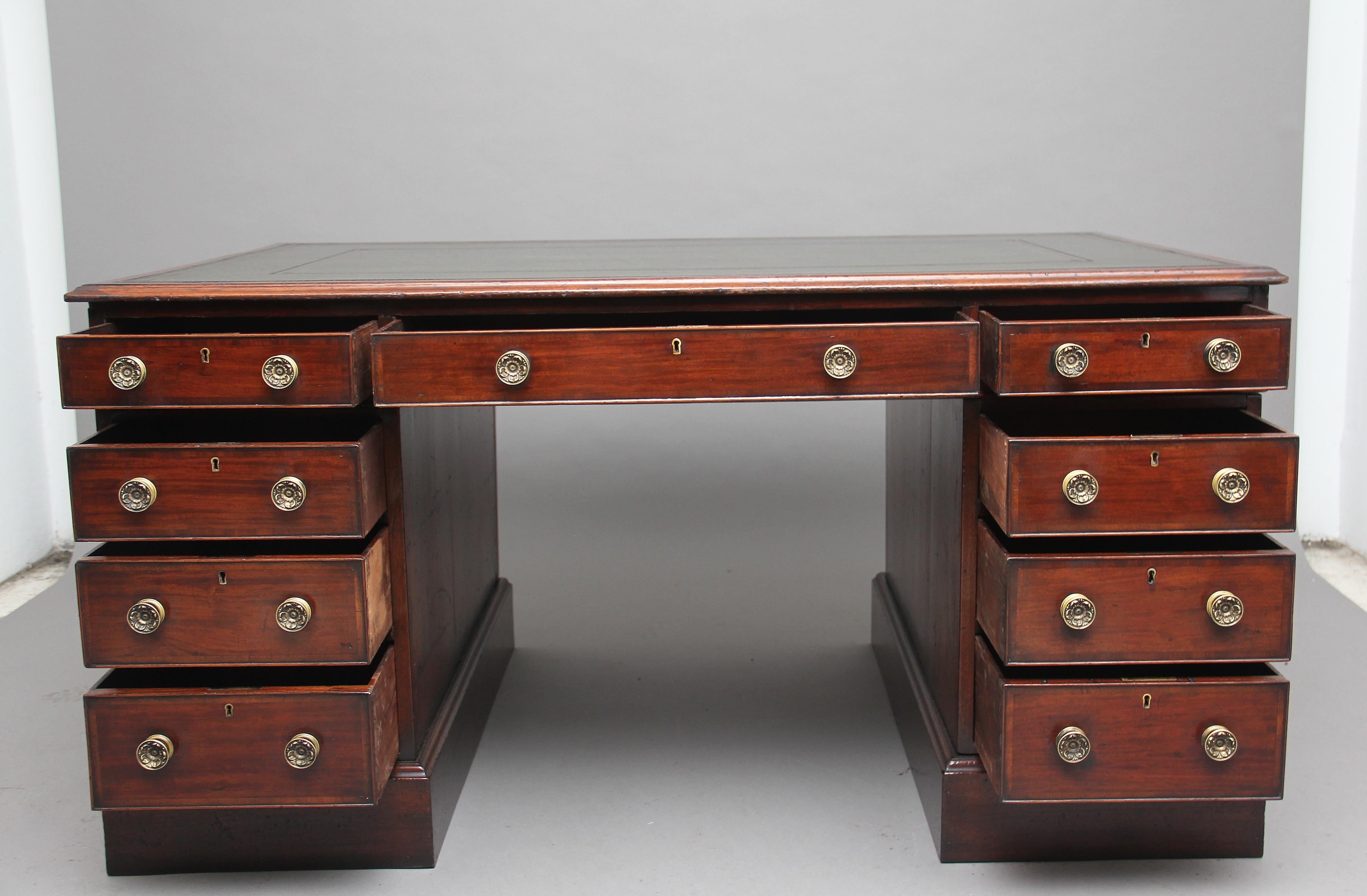 A good quality early 19th century mahogany twin pedestal partners desk, the moulded edge top having a green leather writing surface decorated with gold and blind tooling, the front of the desk having an arrangement of nine graduated, mahogany lined