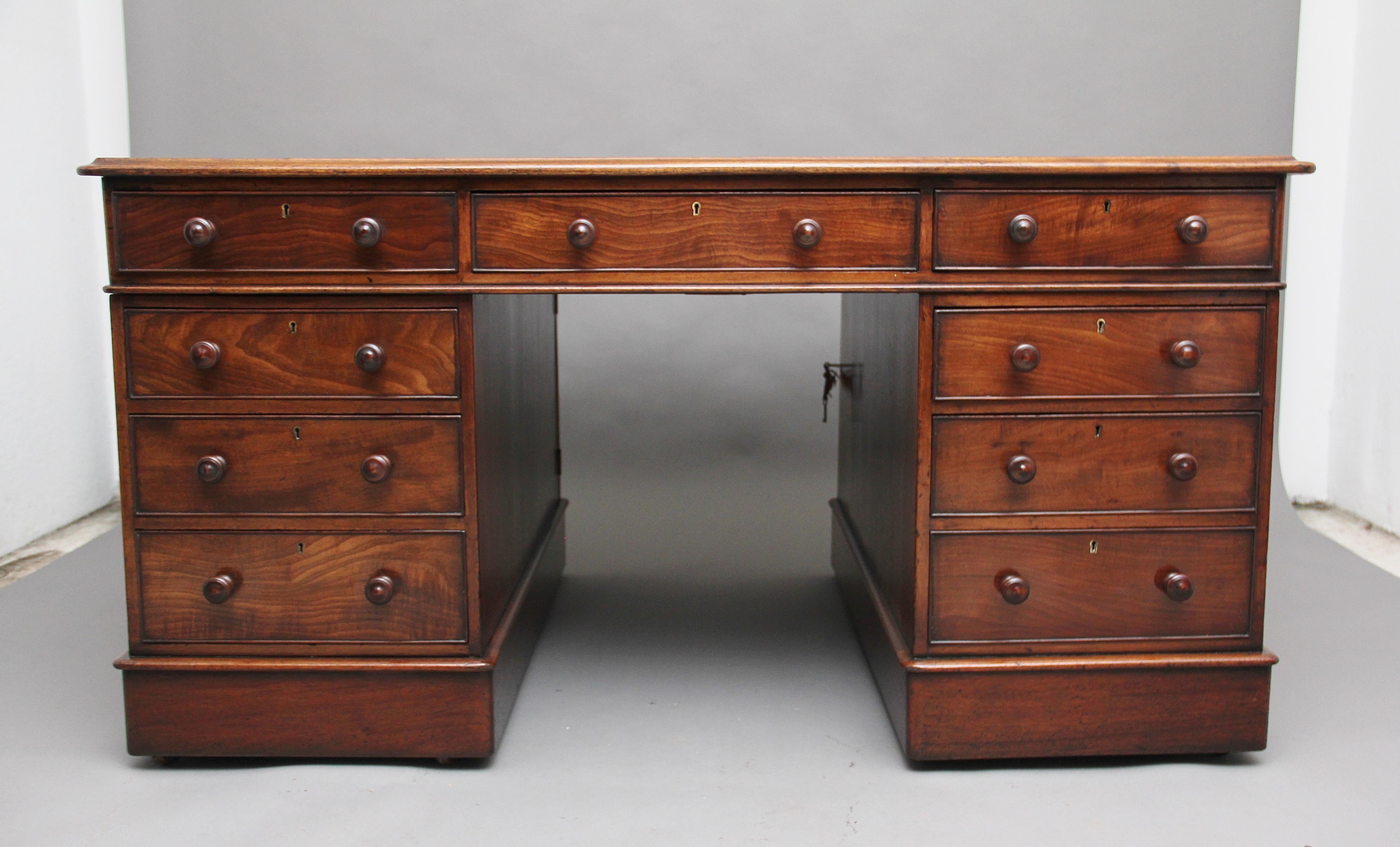 Early 19th century mahogany partners desk, the moulded edge top having a burgundy colored leather writing surface decorated with gold and blind tooling, the desk has an arrangement of nine graduated mahogany lined drawers at the front with turned