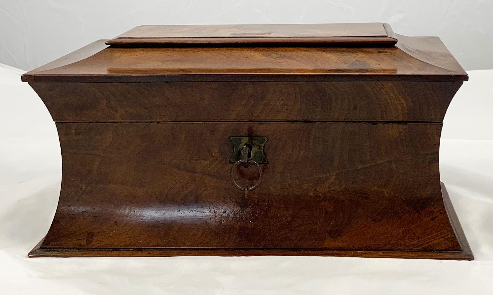 An early 19th century mahogany tea caddy. Of shaped rectangular form. The hinged cover opening to reveal a cut glass mixing bowl flanked by two lidded compartments.