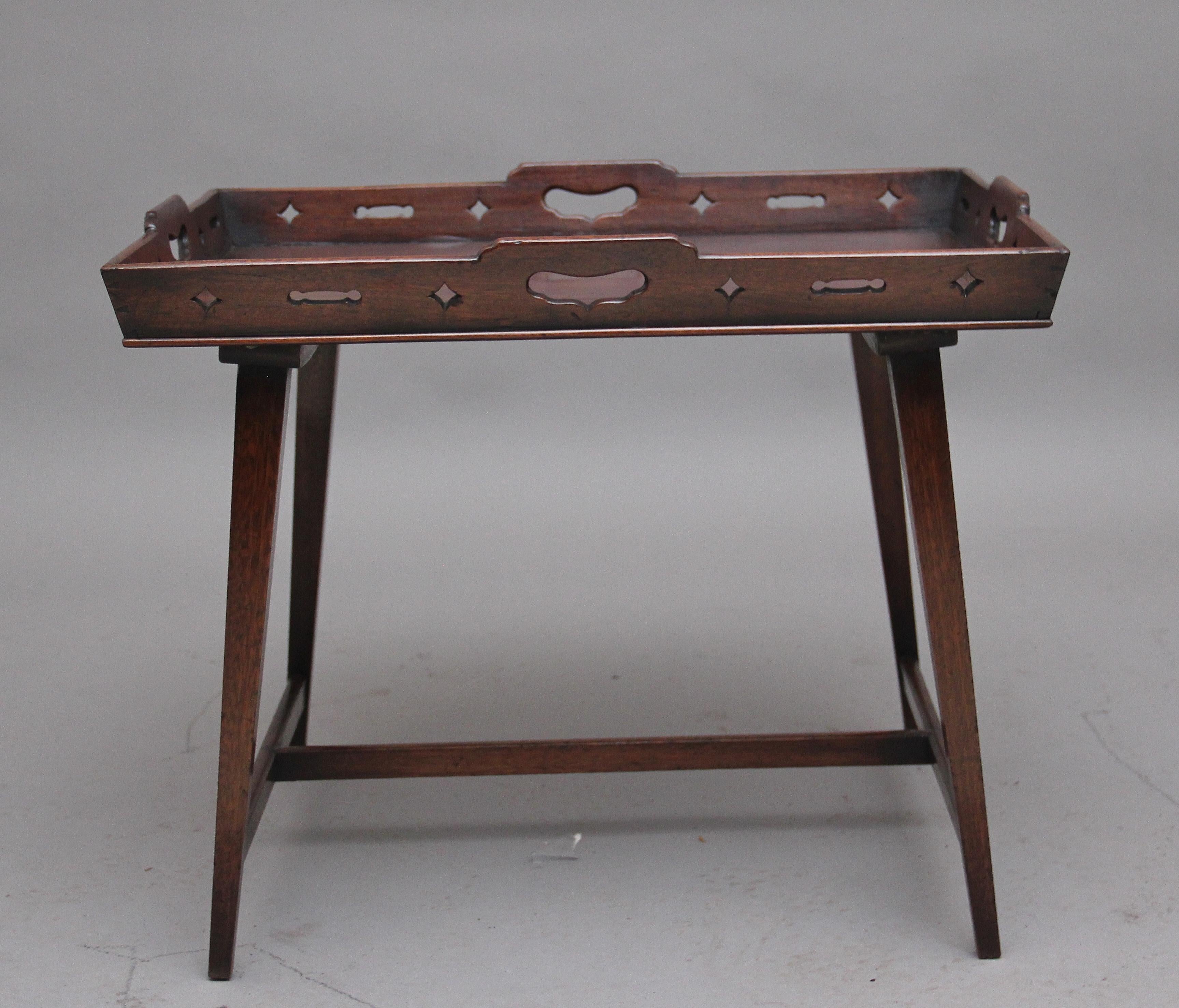 Early 19th century mahogany tray top table on later stand, with handle grips to each side and having pierced decoration to the raised surround, the tray raised on square tapering legs united by an H stretcher, Circa 1810.