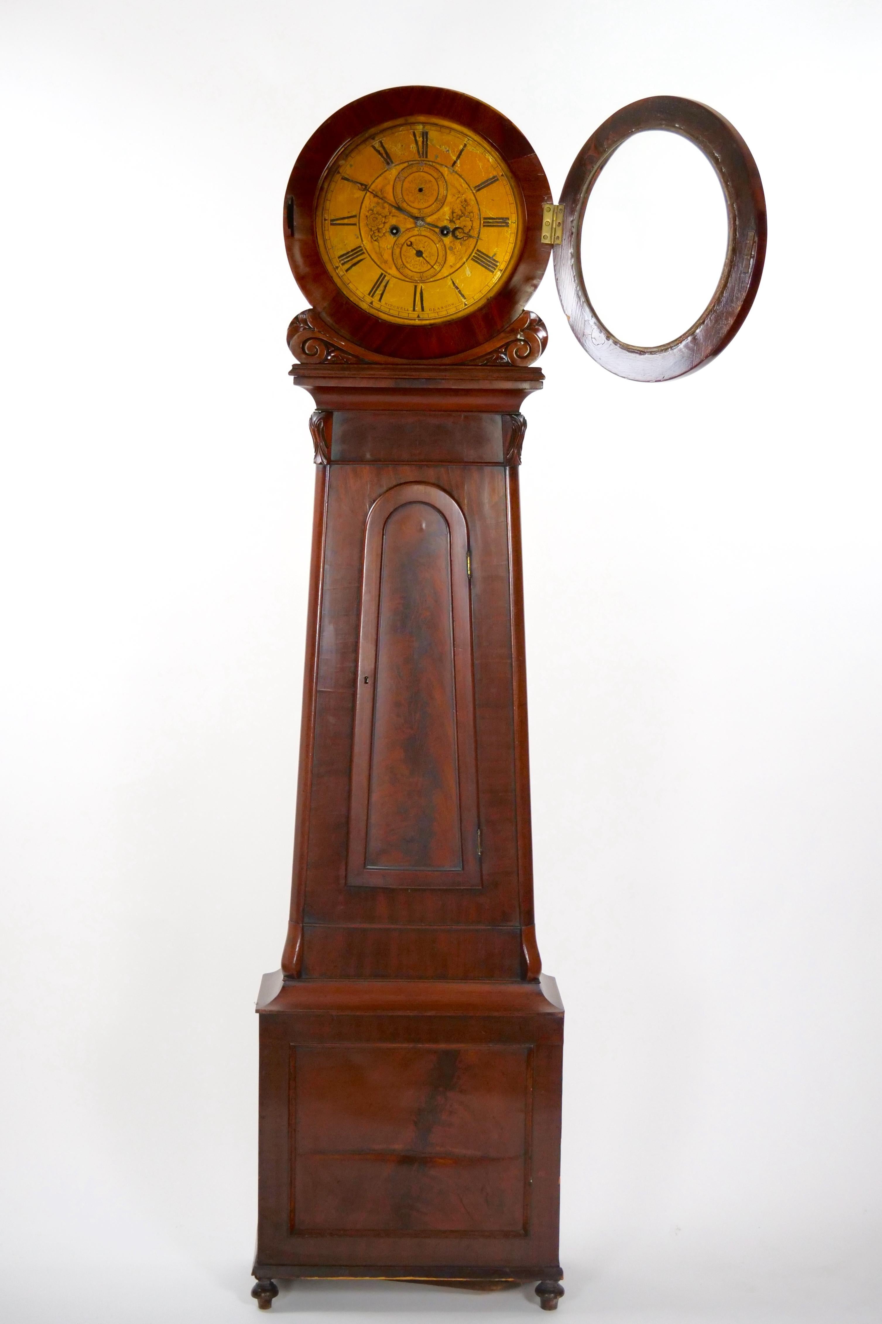 Transport yourself back in time with this exquisite Early 19th Century Mahogany Wood Scottish Drumhead Tall Case Clock. Encased in a rich mahogany frame adorned with banded veneer panels, this clock exudes timeless elegance and historical charm.