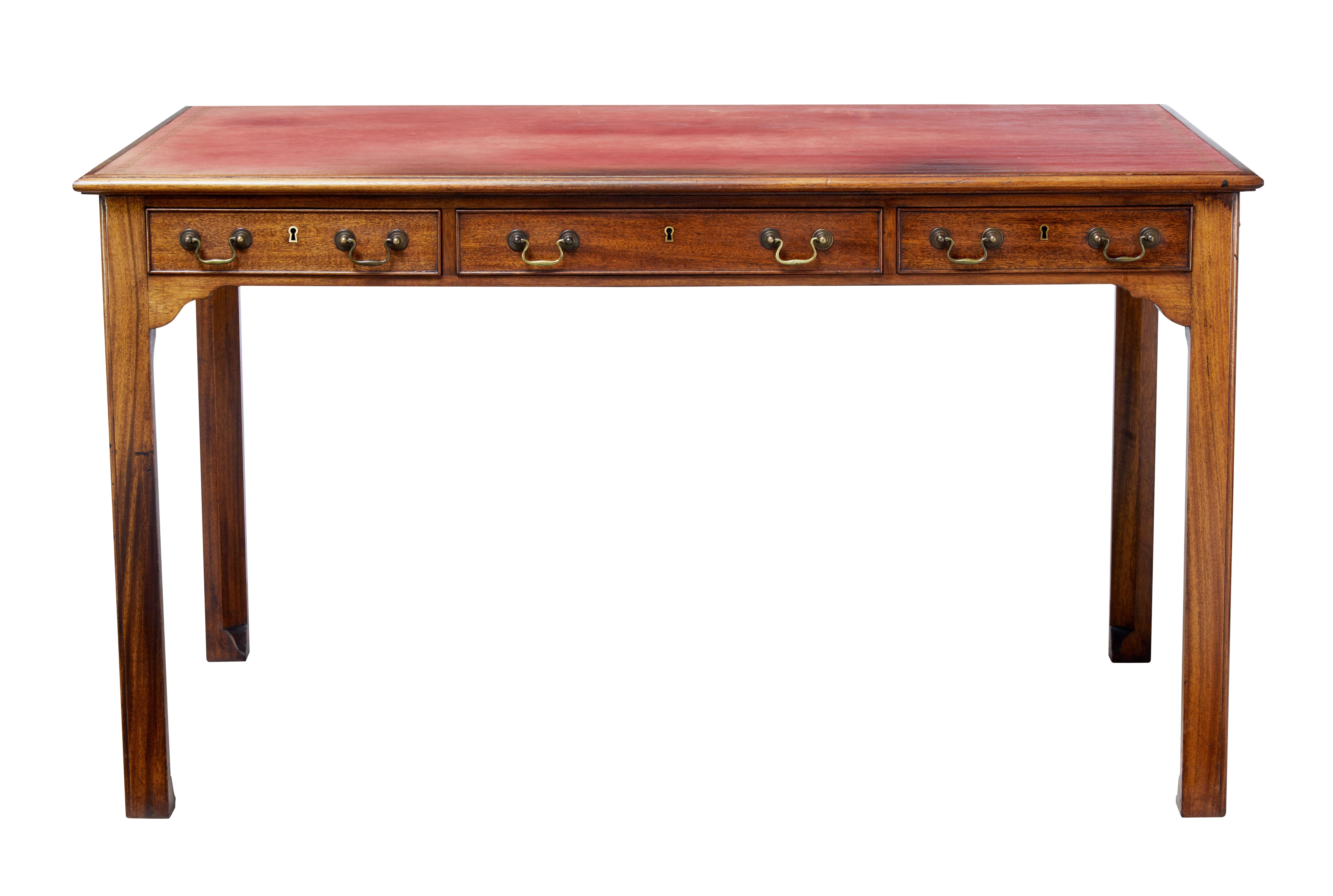 Late George III English writing table with leather top.

Desk front with three drawers below the writing surface and original brass swan neck handles. Dummy to reverse with further handles to the sides.

Possibly the original red leather writing