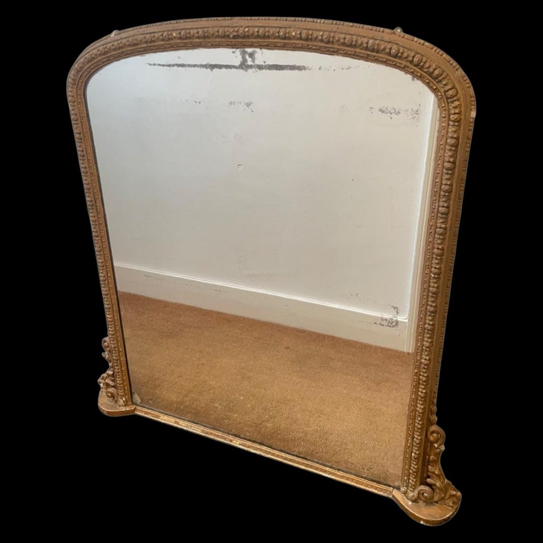 
Nestled within the grandeur of an early 19th-century estate, a magnificent mantle mirror stands as a testament to a bygone era of elegance and sophistication.

This sizeable mirror, though showing signs of wear and age, exudes a timeless charm that
