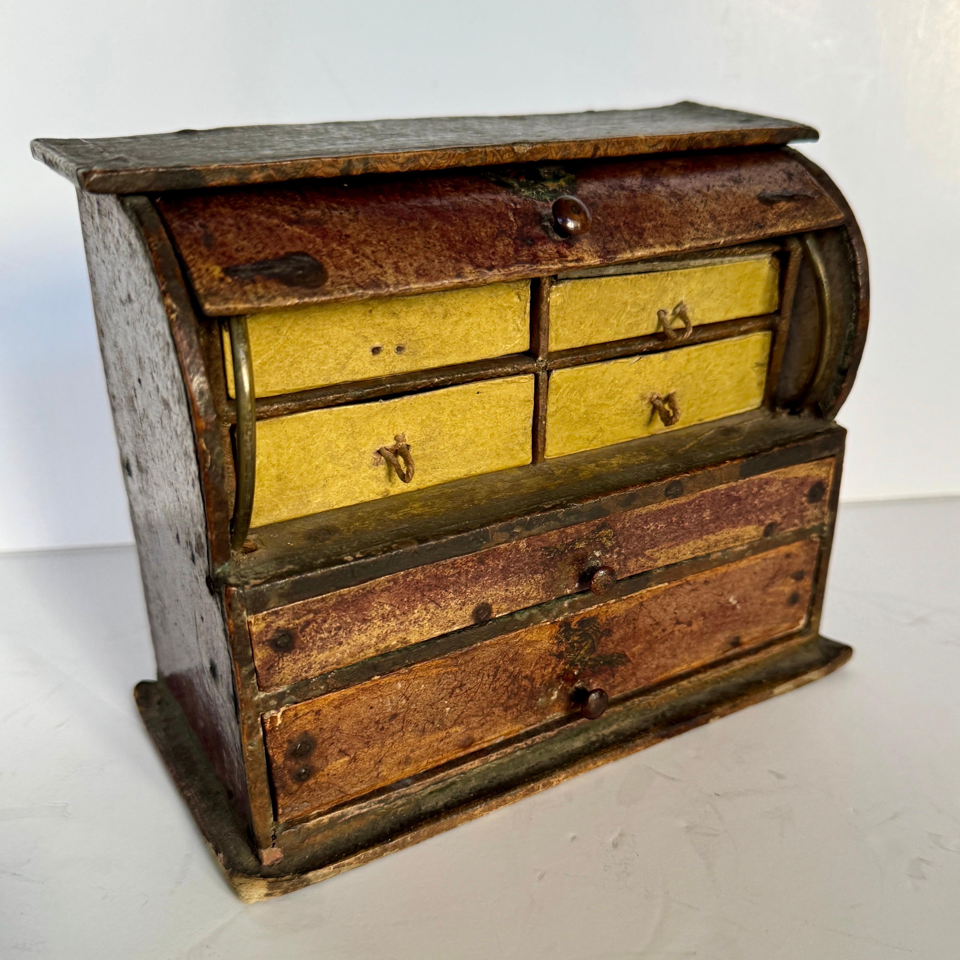 Cette boîte en bois miniature vintage a six tiroirs et beaucoup de caractère et de patine. Certains tiroirs sont tapissés de faux papier marbré. Cette magnifique pièce peut être utilisée pour ranger des bijoux ou faire partie d'une collection.