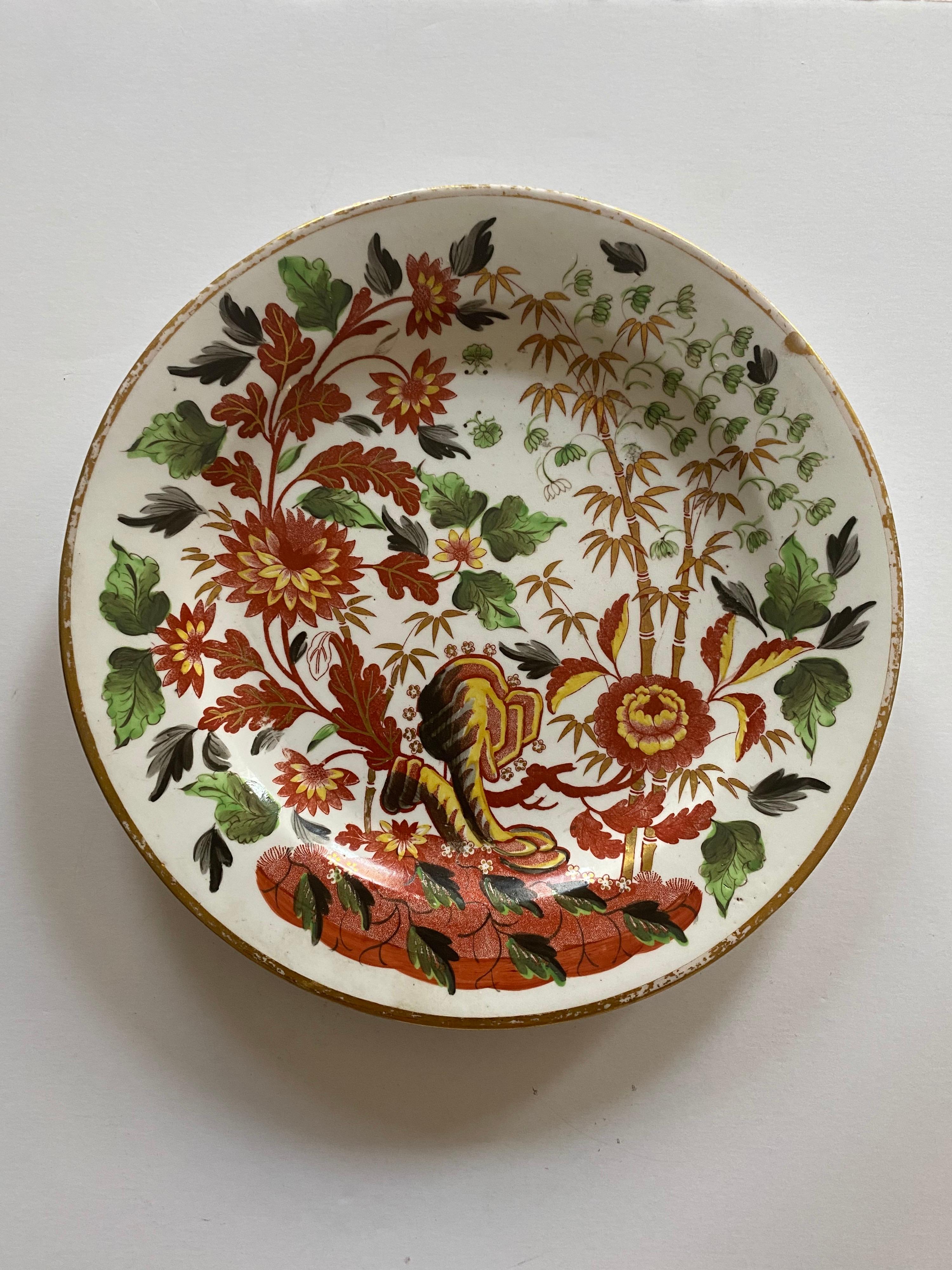 A pair of early Minton porcelain plates, unusually decorated with a red bat-print of Oriental flowers and bamboo branches, overpainted with colourful enamels and complemented by a gilt rim.

Made in England, circa 1806.

Light wear; minor loss to