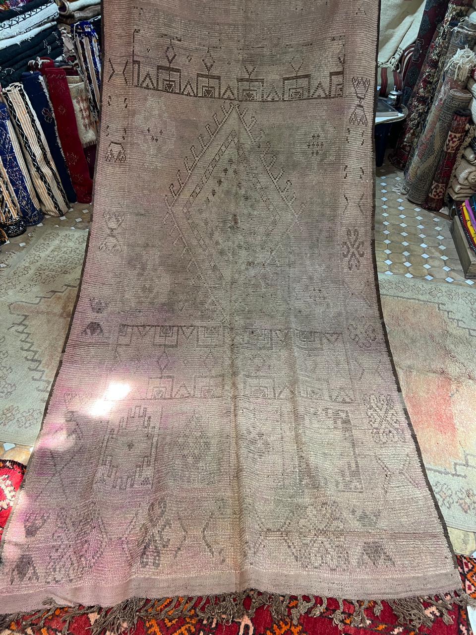 This rare and evocative early 19th-century Moroccan tribal rug is a masterwork of minimalist geometry and subdued symbolism, woven in the remote High Atlas region by indigenous Berber artisans. Estimated to date from around 1820, the piece showcases