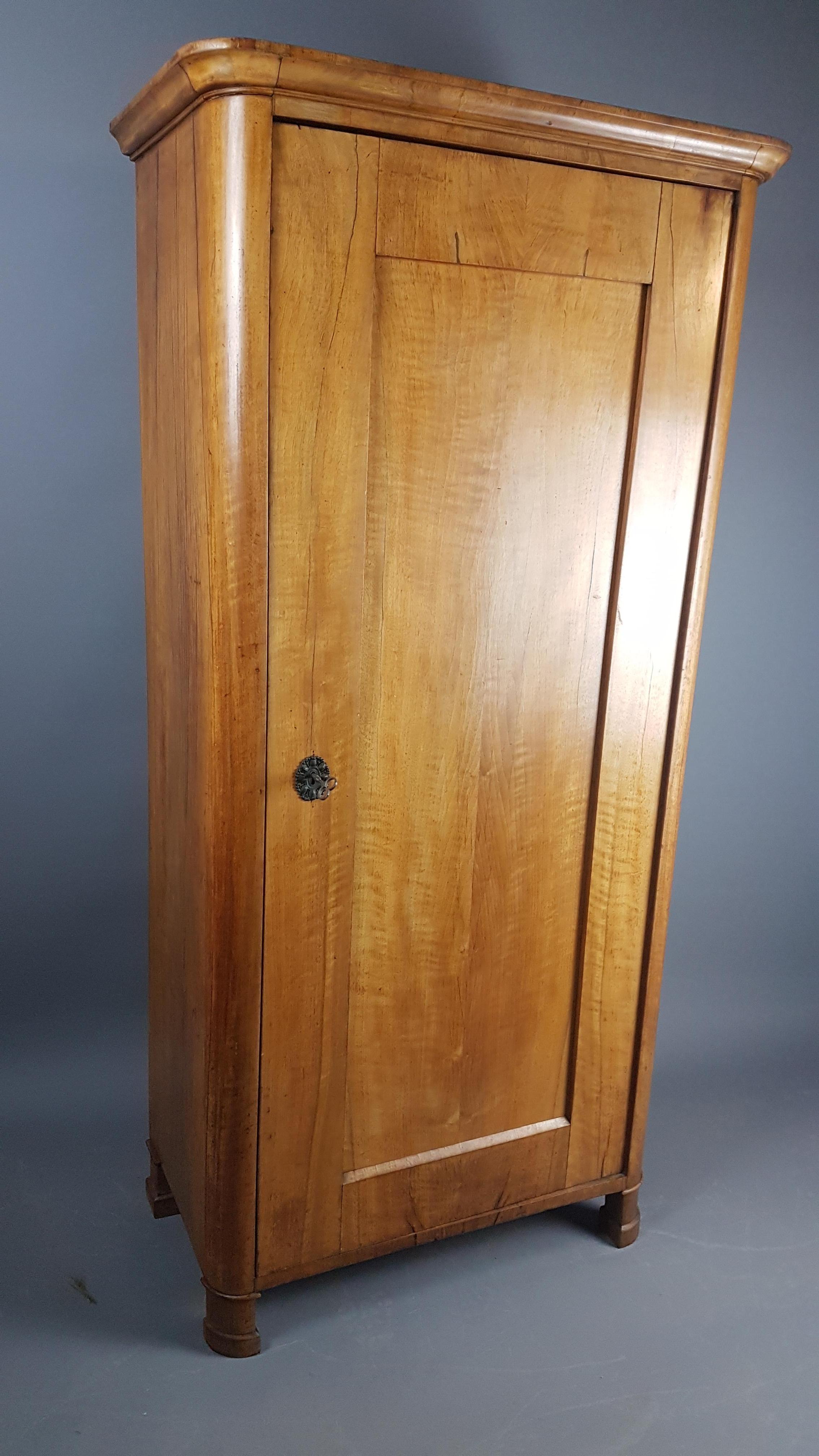 A nice narrow example of a pale walnut Biedermeier armoire or cupboard. The shelves are removable however are in set positions, it retains it's original finish and it is in overall nice condition with normal marks & knocks from use. The lock has a