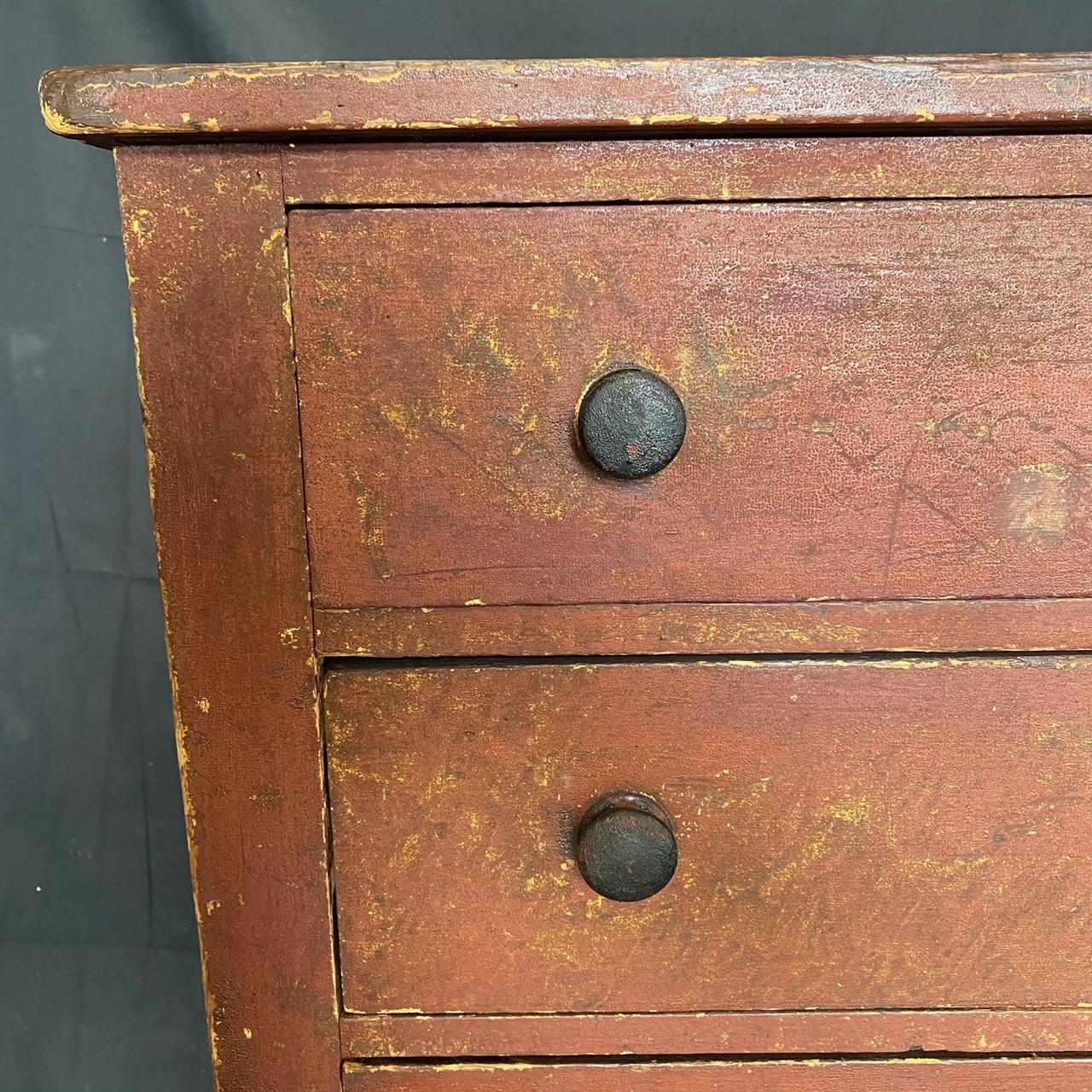 Super early and Classic original 1830s early American pine chest of drawers from Maine with original rustic red paint and knobs, plank top and back, and turned legs. 
#5452.

   