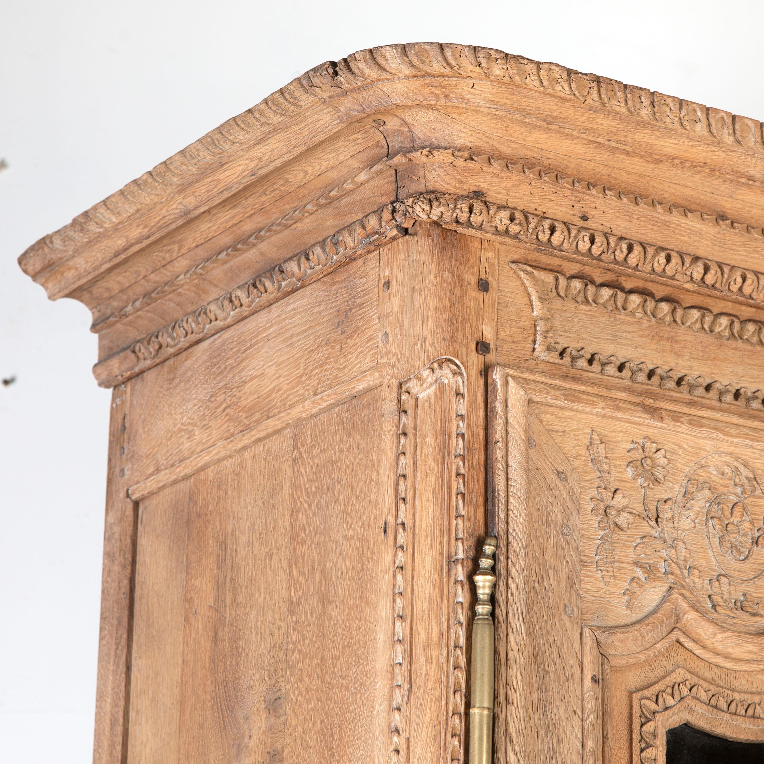 Fine early 19th Century two-part buffet from Normandy.

This piece is beautifully hand-carved and is composed of bleached oak. 

The glazed top section features three internal shelves, a single shelf in the base, and its original brass fittings