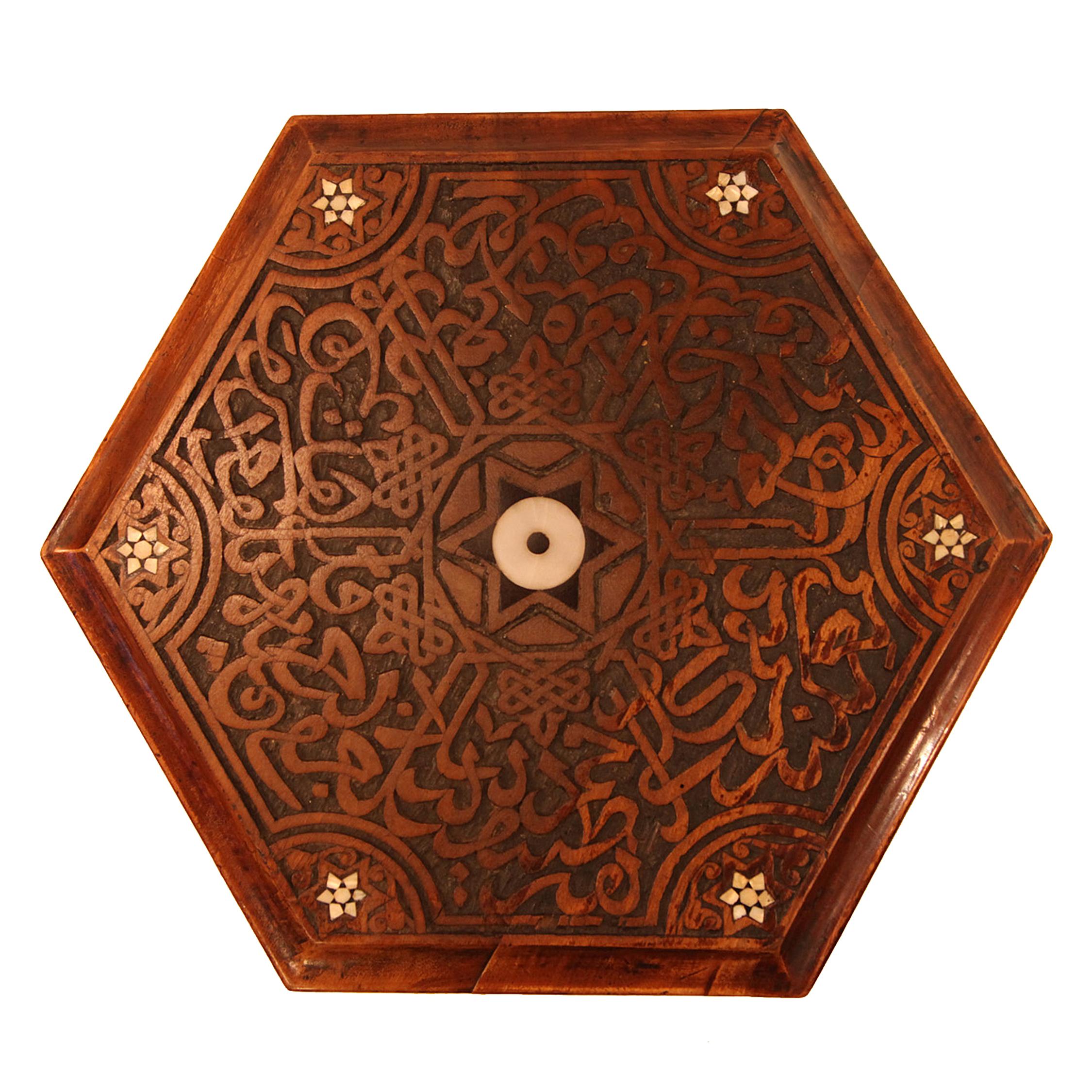 The tabletop with carved cutout shapes and mother of pearl inlay above an intricately carved base also with mother of pearl inlay, on ball feet.