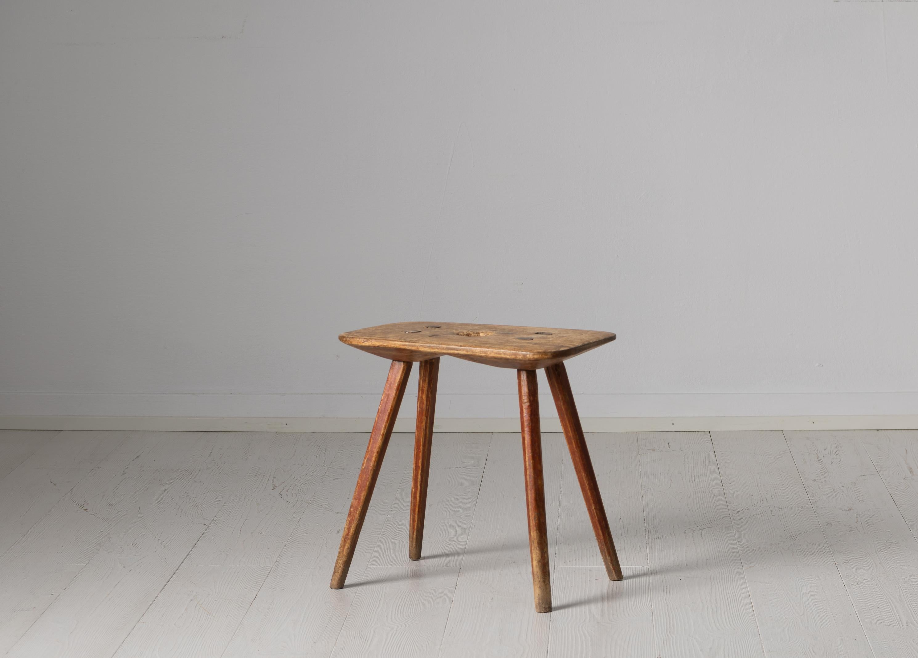 Northern Swedish charming folk art stool from the early 19th century. The stool is made in pine and it has the original worn patina of time. The model and construction is primitive but the stool has some smaller details like the profiled edges on