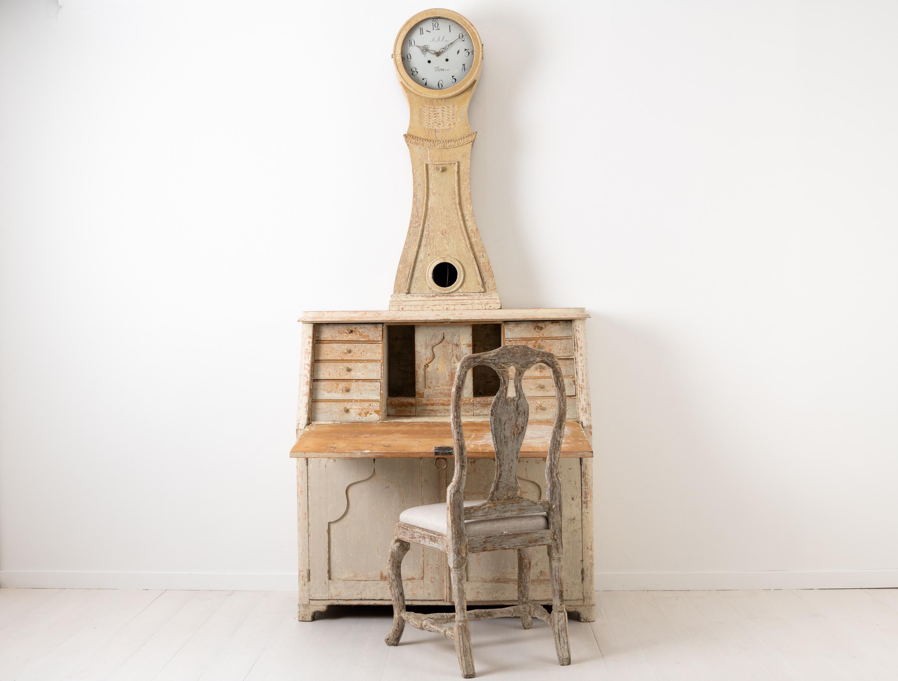 Northern Swedish clock secretary from circa 1820. The clock is in two parts and dry scraped to the original light paint. Antique hardware and lock and key in working condition. The interior to the desk has drawers on each side and an open