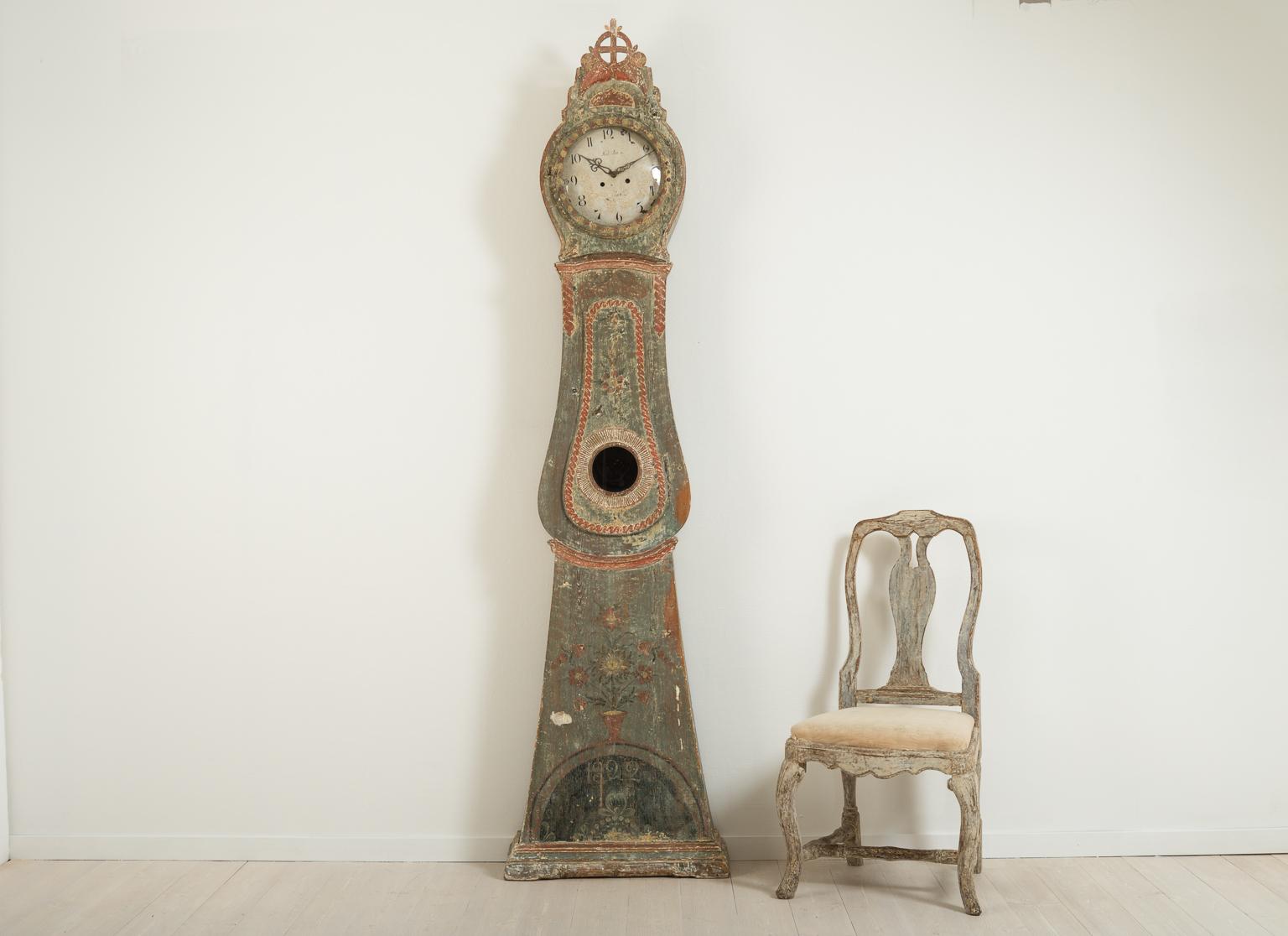 Long case clock from northern Sweden. The clock has carved wooden decorations and is dry scraped to original paint. Dated 1822. Original mechanism, pendulum and weights. The clock face have minor marks, see picture. The clock was working at the time