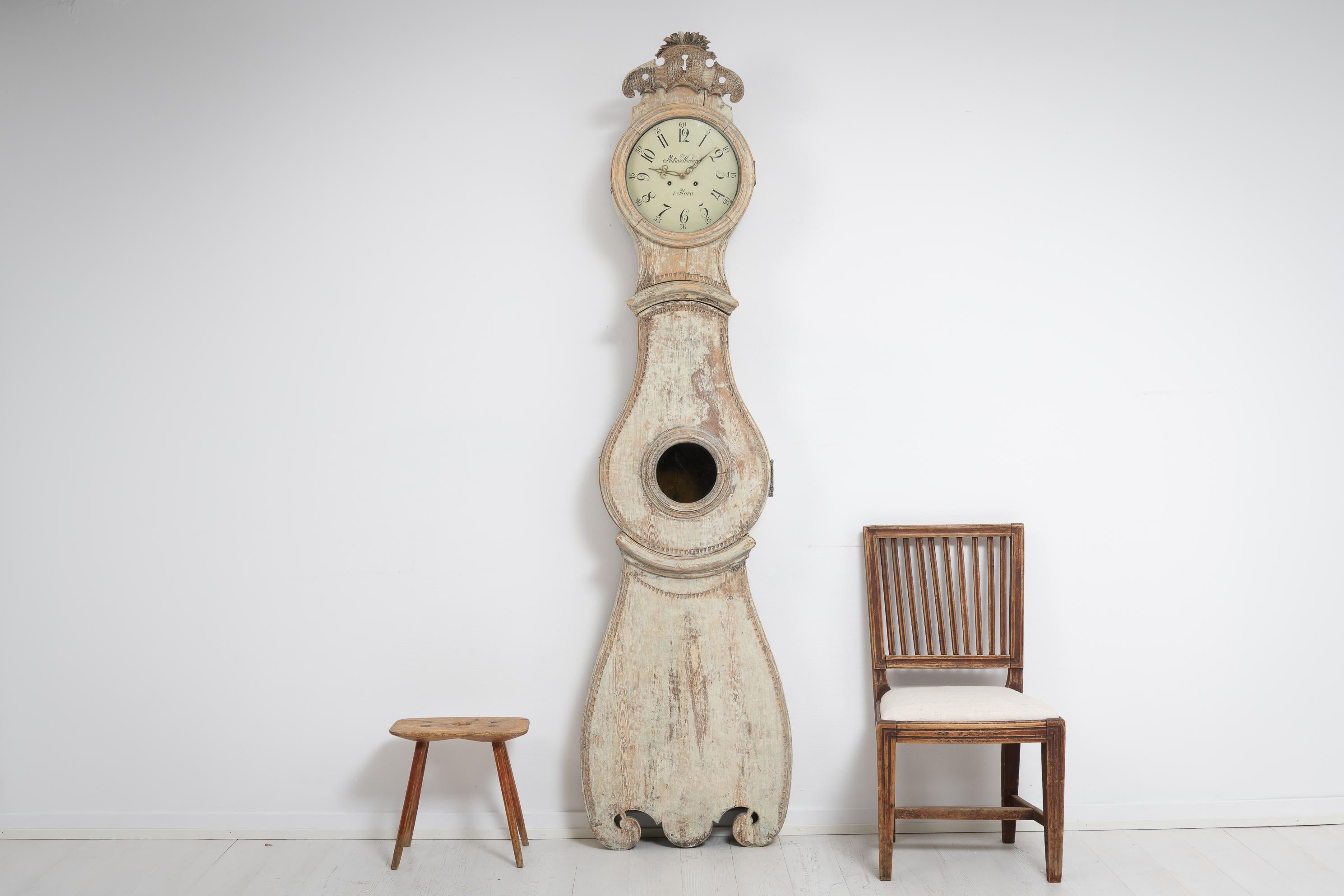 Northern Swedish rococo long case clock made around 1810 to 1820. The clock is dry scraped to the original first layer of paint and it’s distressed with the patina of time. This clock has a large decorations at the top and a subtle hand carved