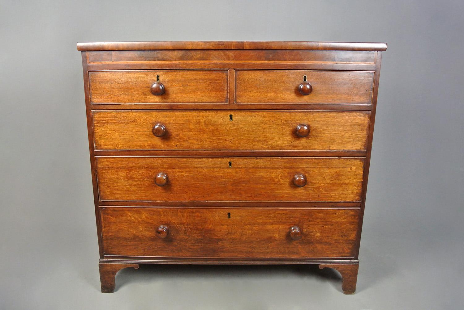 A large, substantial and very usable oak chest of drawers made by hand in c. 1840 and retaining its original well turned knob handle.  The attractive deep frieze is crossbanded with walnut and inlaid with  satinwood banding.  The oversailing top has
