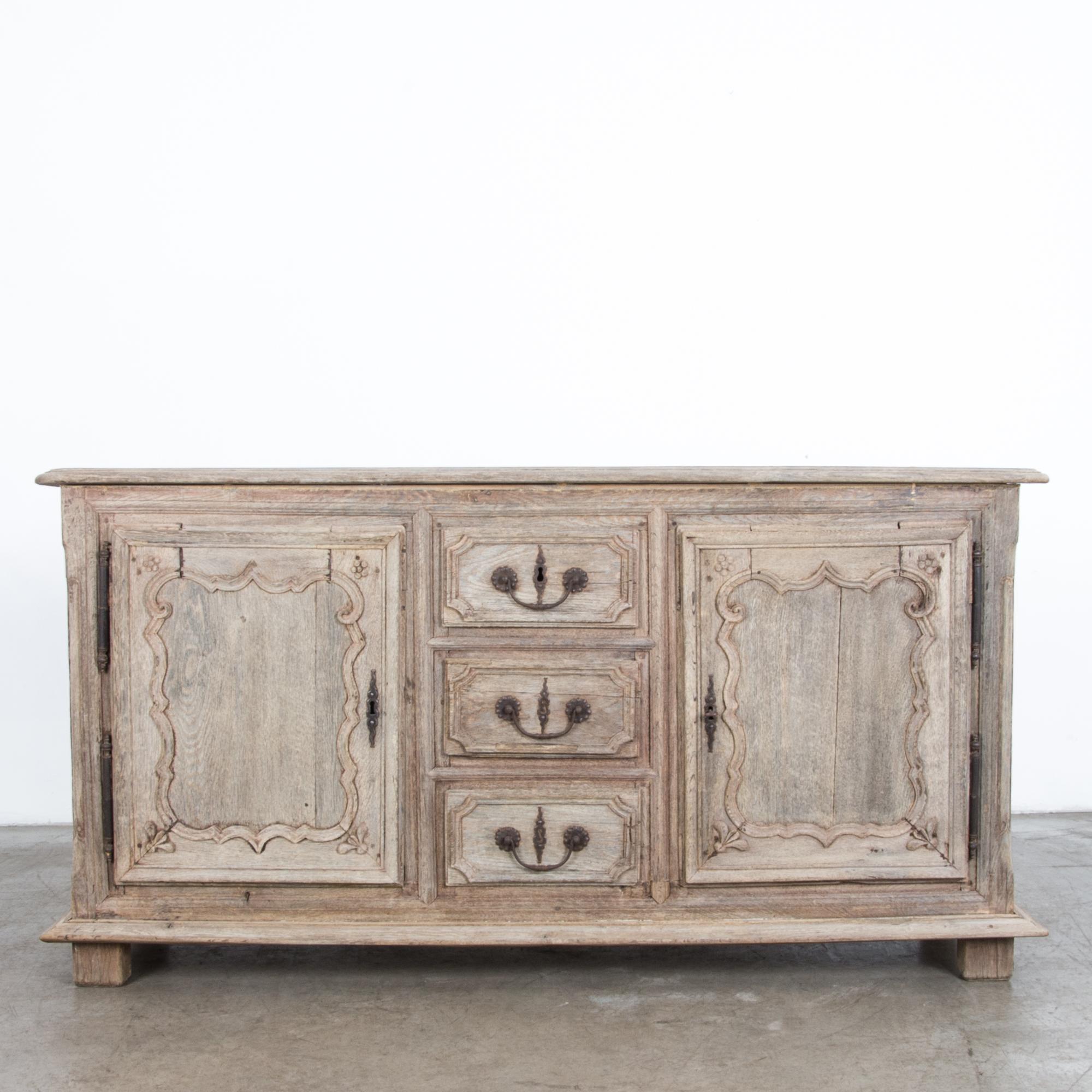 From France, circa 1800, a two-door oak sideboard with three center drawers. In a stylish light finish, sturdy oak has been cleaned and polished with an oil & wax finish, enhancing the natural wood texture and original iron hardware. Chic while