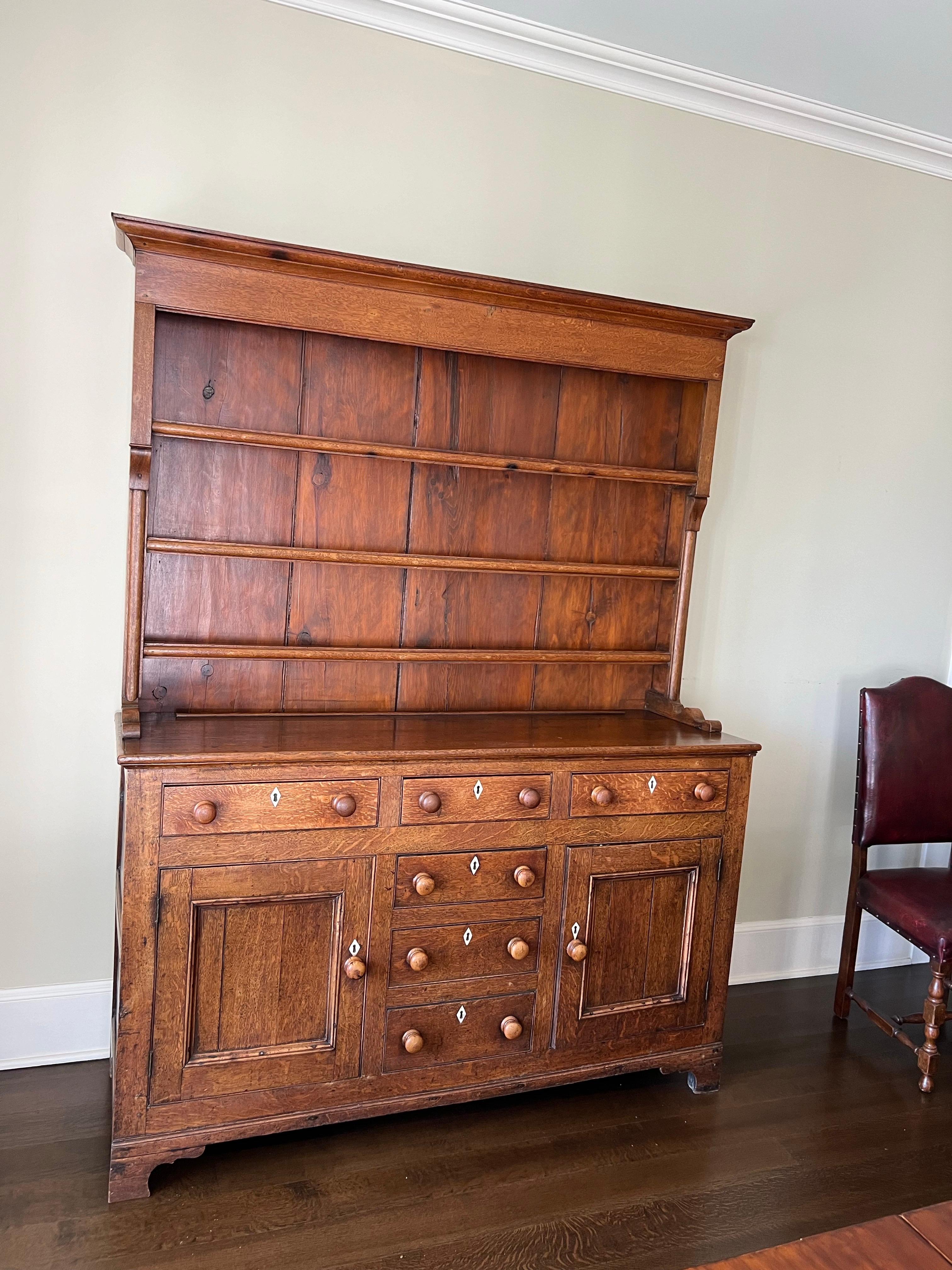 Early 19th Century Oak Welsh Hutch Cupboard
This handsome and useful piece has three graduating shelves on the upper hutch sitting atop a cupboard with three drawer over two doors on either side of three more central drawers. The drawers and doors