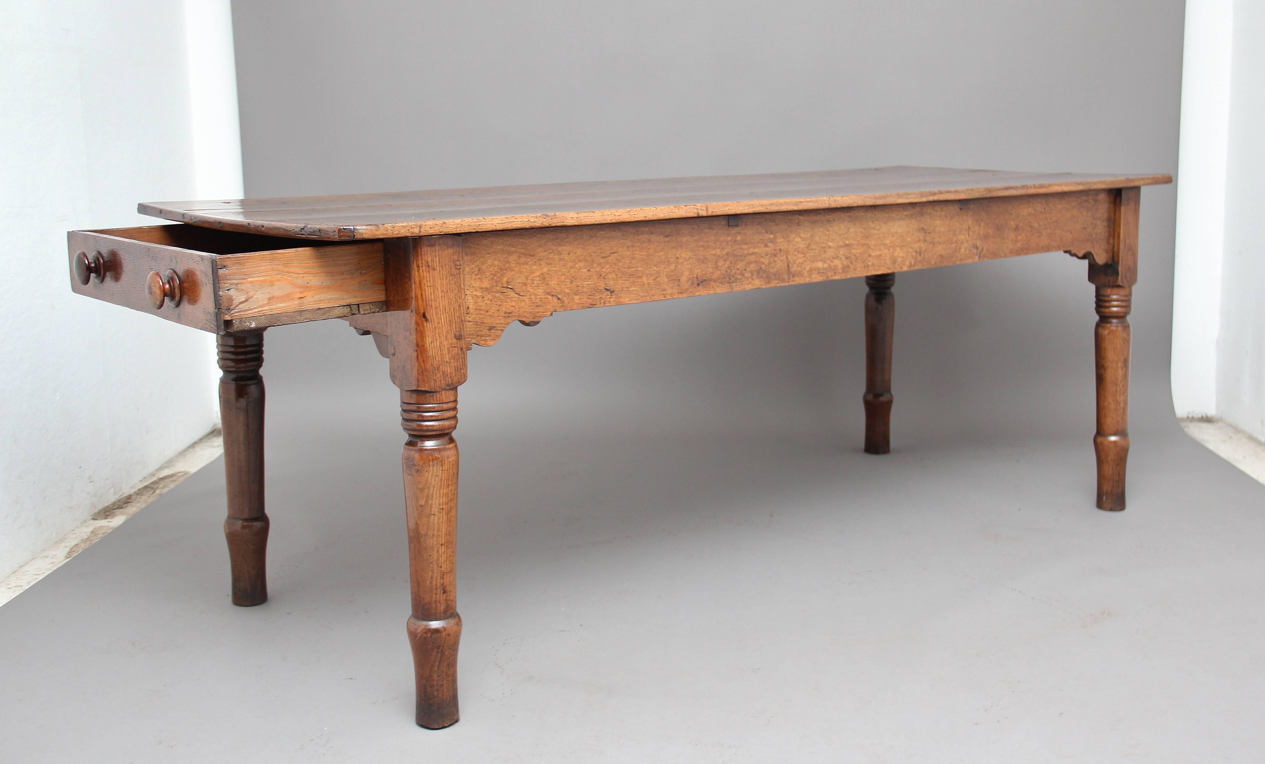 A superb quality early 19th century oak farmhouse table, the three plank top having a wonderful patina above a frieze which is shaped at the corners, with a drawer at one end of the table with original turned wooden knobs, standing on nice bold