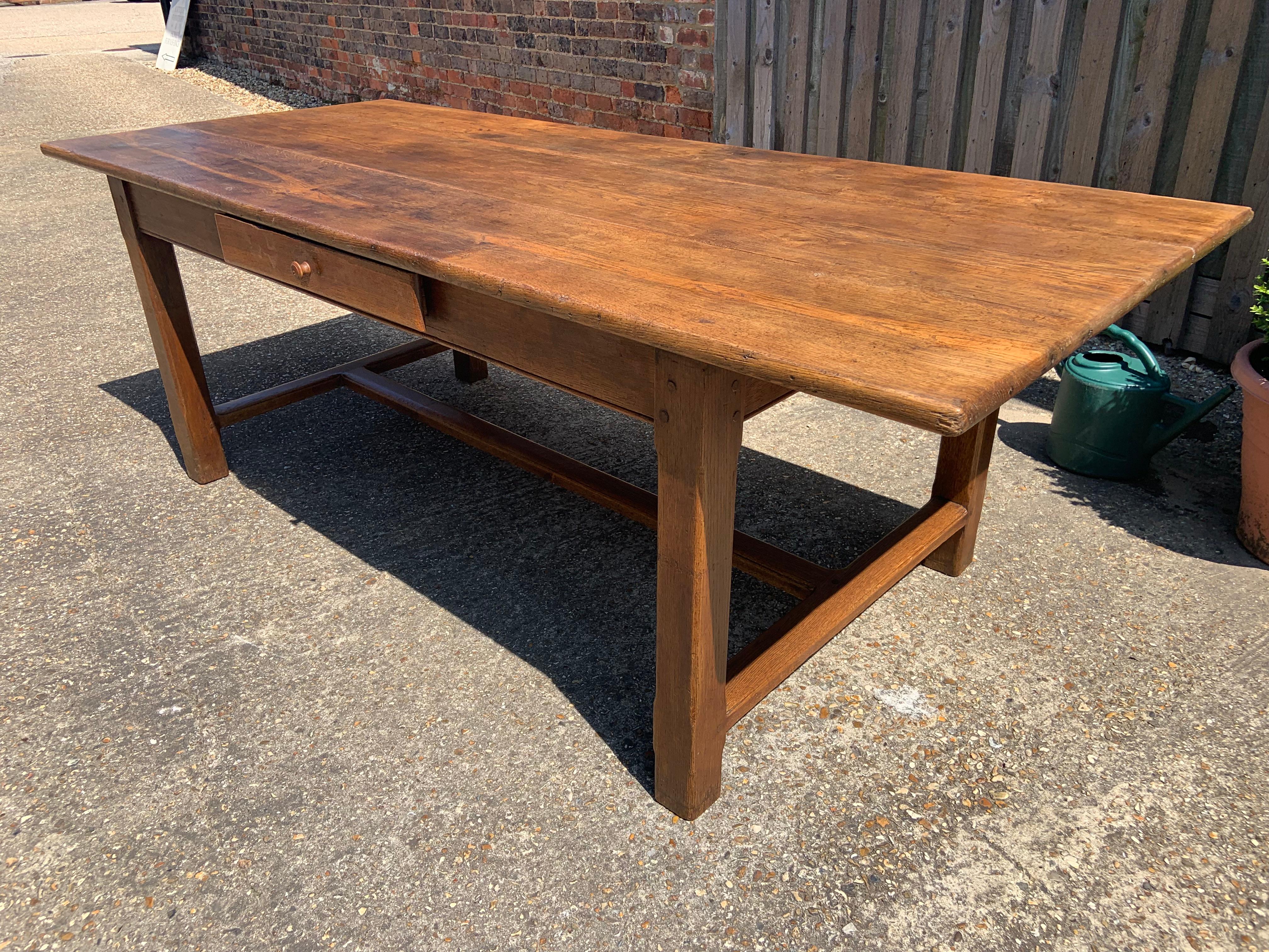 Early 19th century oak farmhouse table with lovely wide three plank top and side drawer. Table sits on a stretcher base.