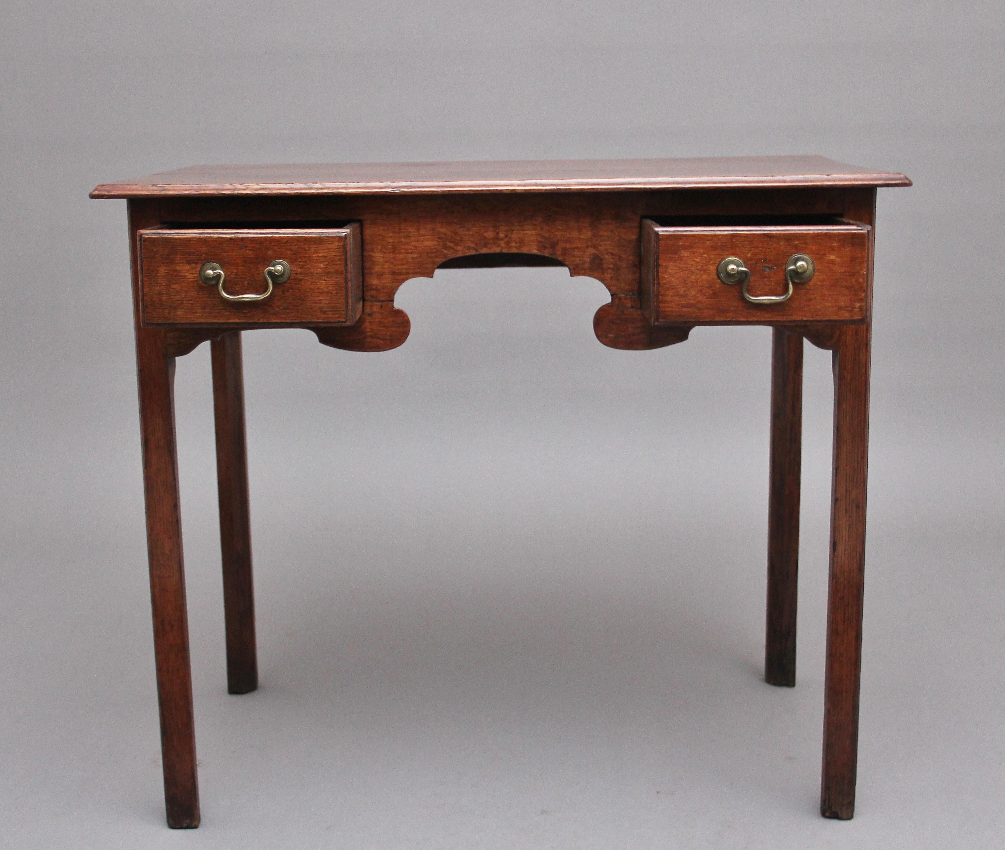 Early 19th century oak lowboy / side table, having a moulded edge top above two oak lined drawer with original brass swan neck handles, having a decorative shaped freeze at the front, standing on square legs. Circa 1800.
