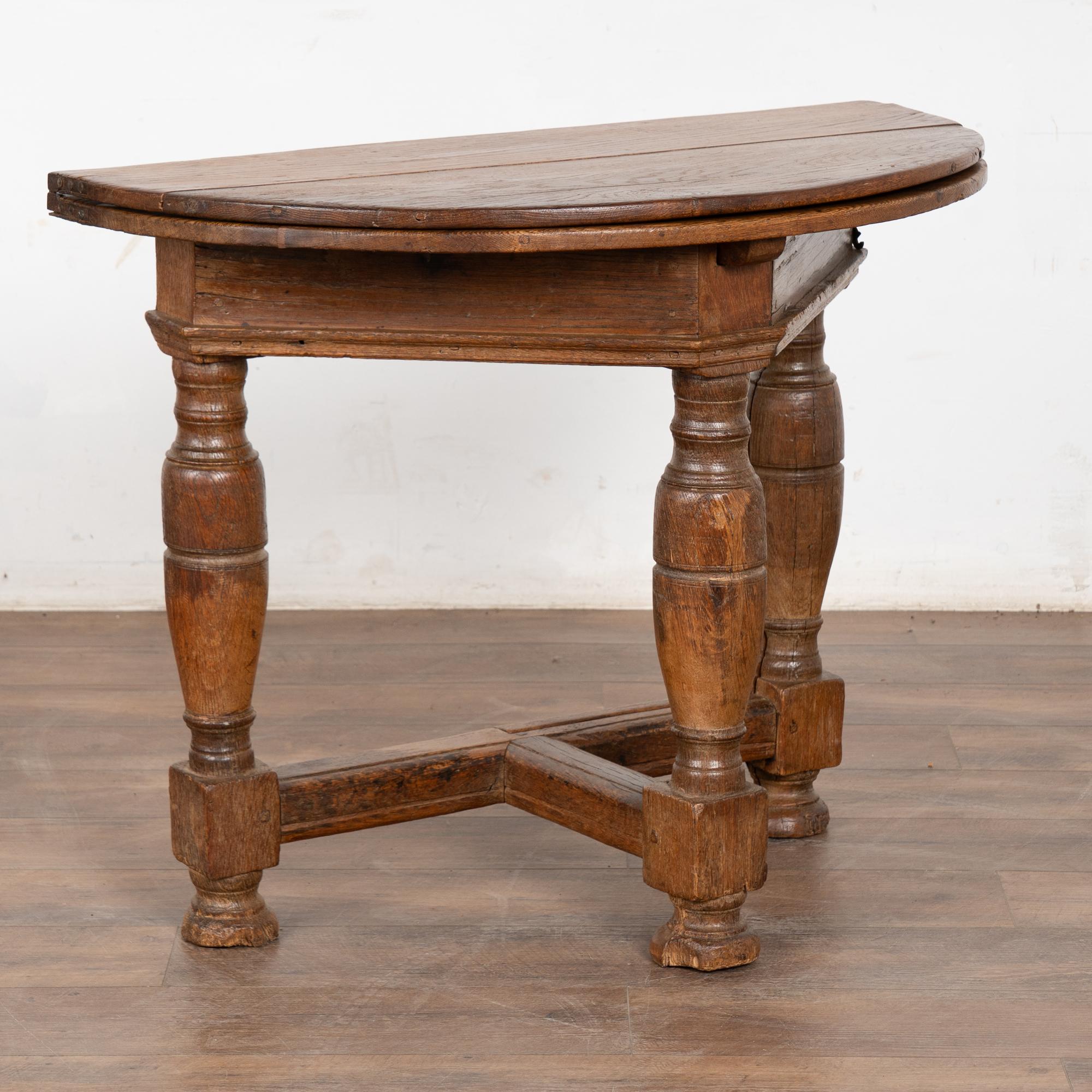 There is wonderful aged charisma to this drop leaf gate leg table that can serve as a side table, game table, demi-lune console or even small kitchen table.
The aged oak has taken on a deep patina after generations of use. 
When closed, the table is
