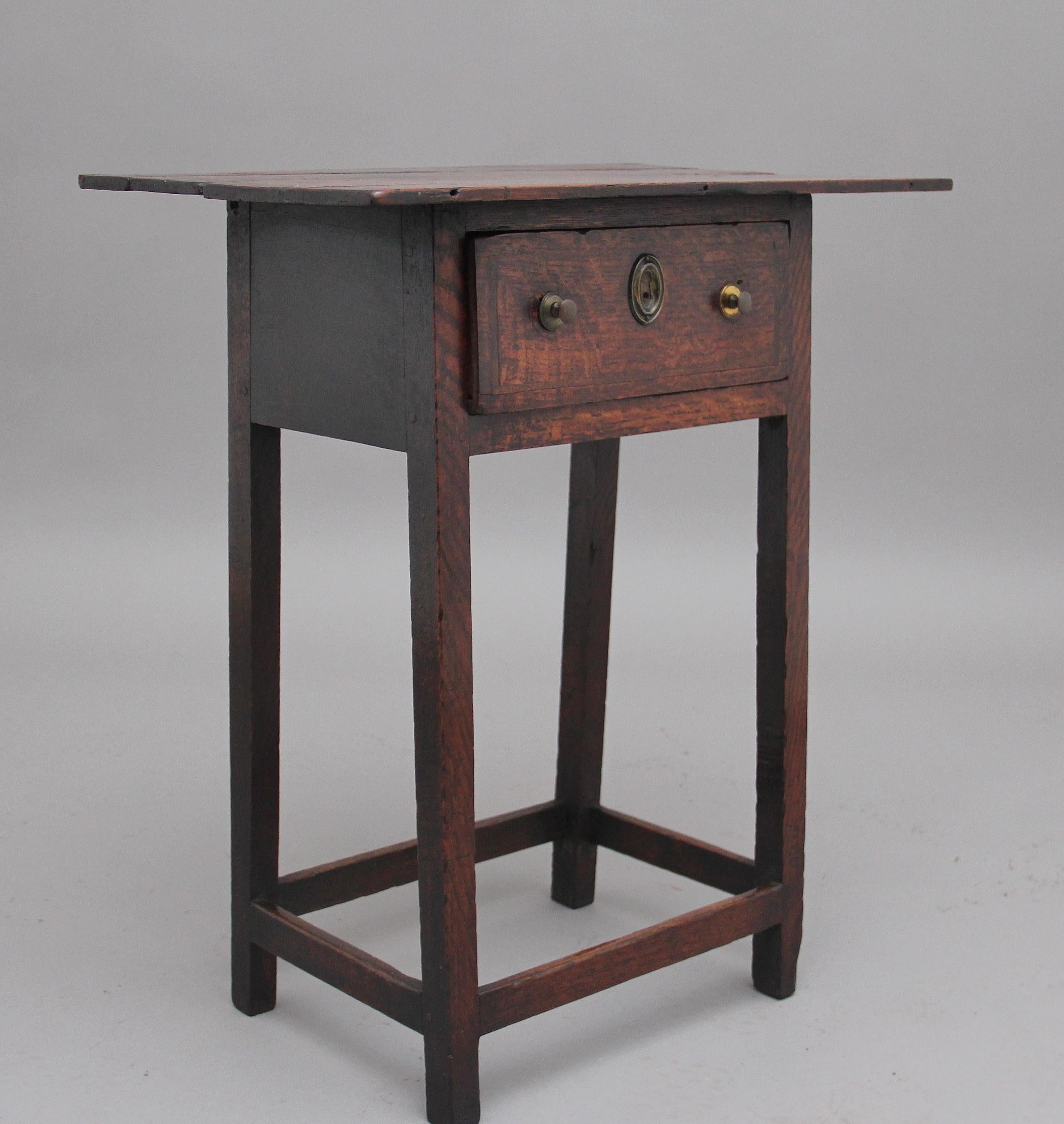 Early 19th century country oak side table, the rustic top above a single frieze drawer with brass knob handles and escutcheons, supported on square legs united by a stretcher, Circa 1810.