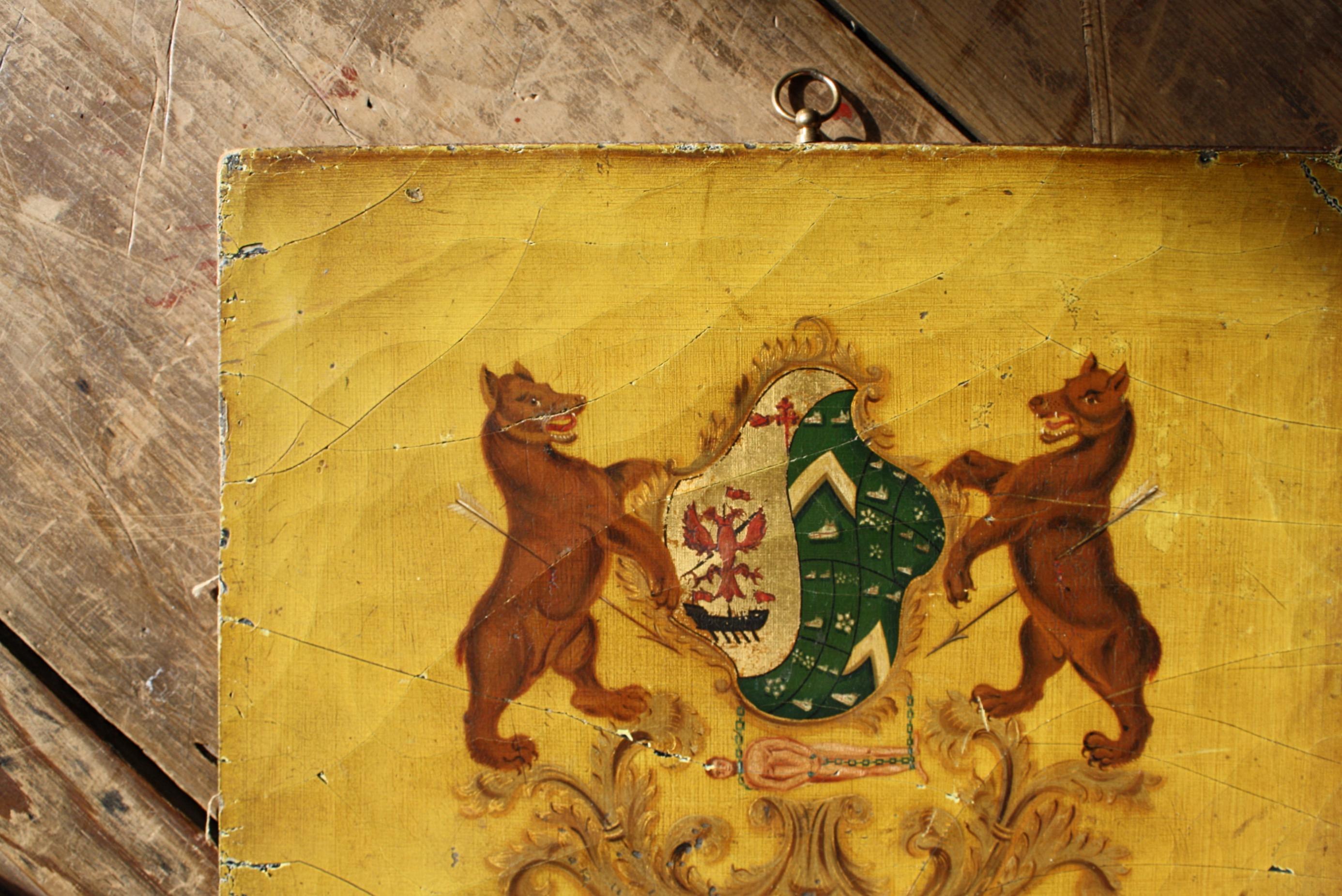 Un bon panneau de carrosse du début du 19e siècle, avec deux ours empalés de part et d'autre des armoiries et un gentilhomme enchaîné se balançant en dessous, le tout peint sur un beau fond moutarde. 

Toile marouflée sur carton, avec un anneau de