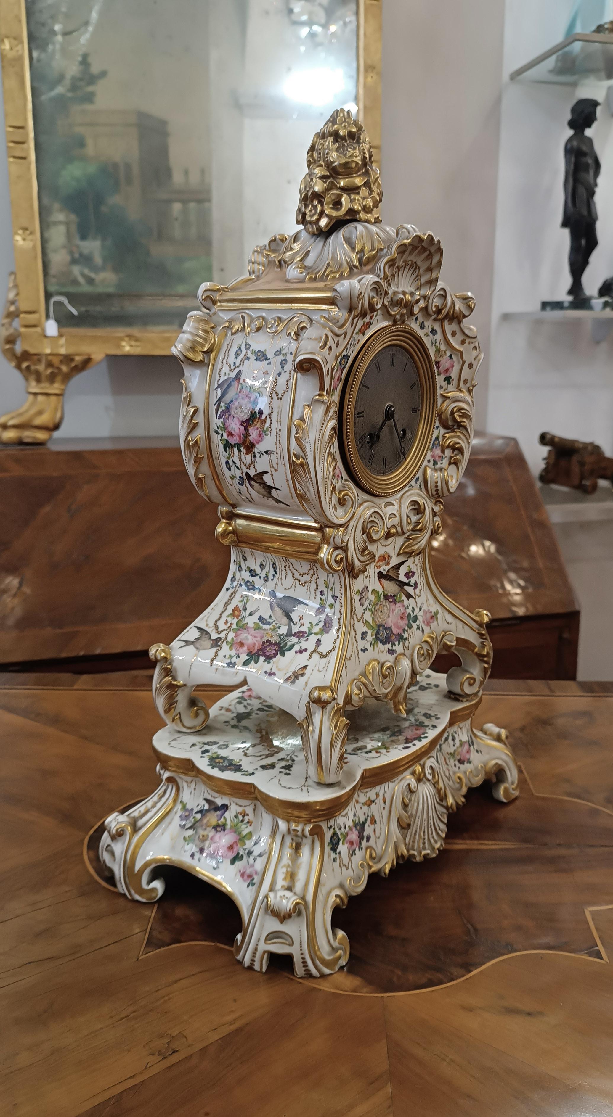 Beautiful and elegant polychrome porcelain clock, with silk thread suspension mechanism. Made from high quality porcelain, it is beautifully gilded and features charming plant motifs, culminating in a golden pine cone. Its surface is also decorated