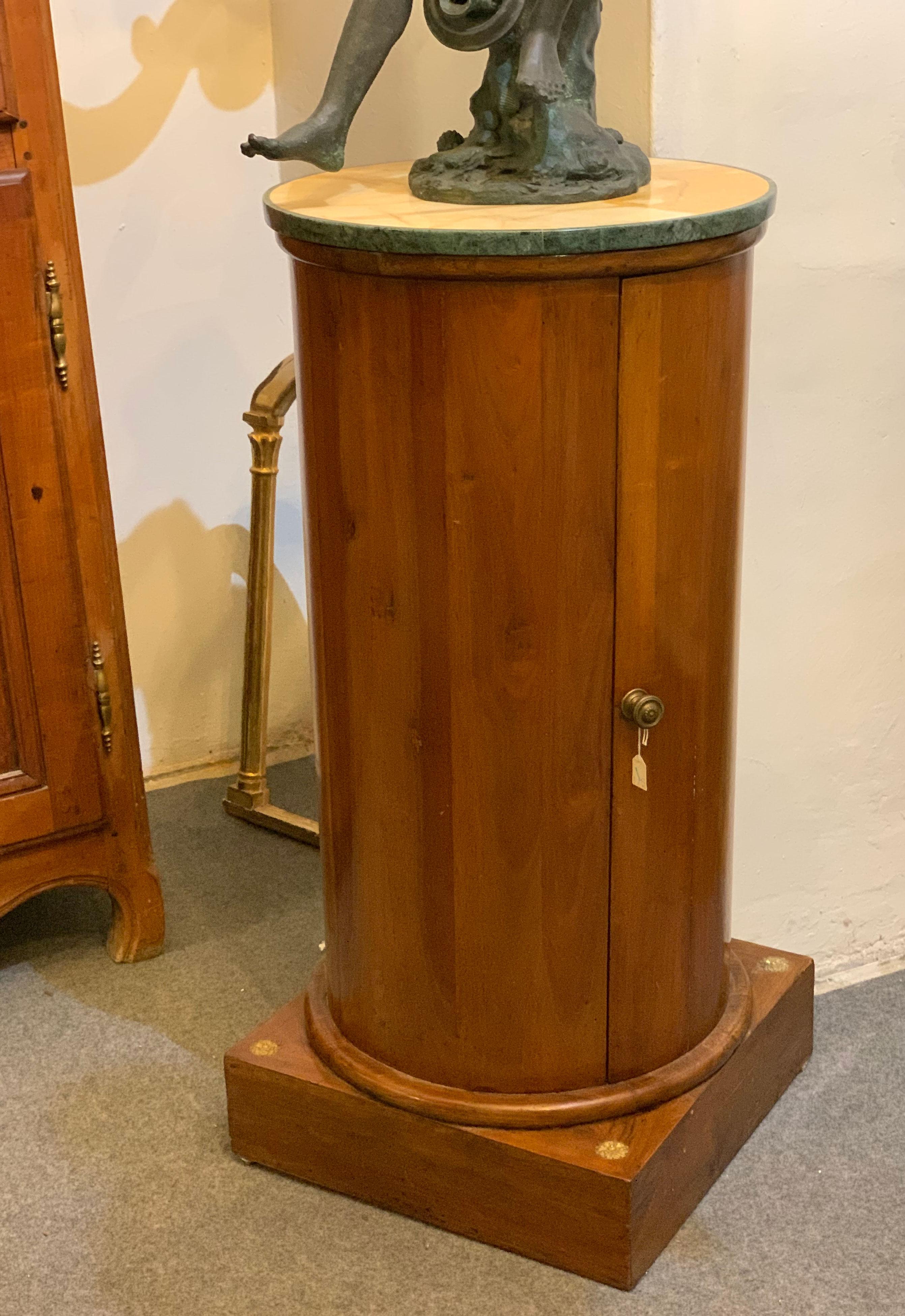 Elegant circular column on a square plinth. The column is entirely veneered in walnut, with the top in yellow Siena marble and the edge in green Prato marble. The piece of furniture has both the function of supporting an object or a lamp and as a