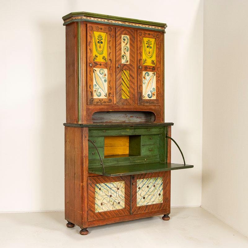 This highly unusual secretary is a special find. The remarkable folk art painted finish is all original, with brick red, salmon, yellow, blue and green all used to create the delightful flourishes. The interior desk is painted green and holds 8
