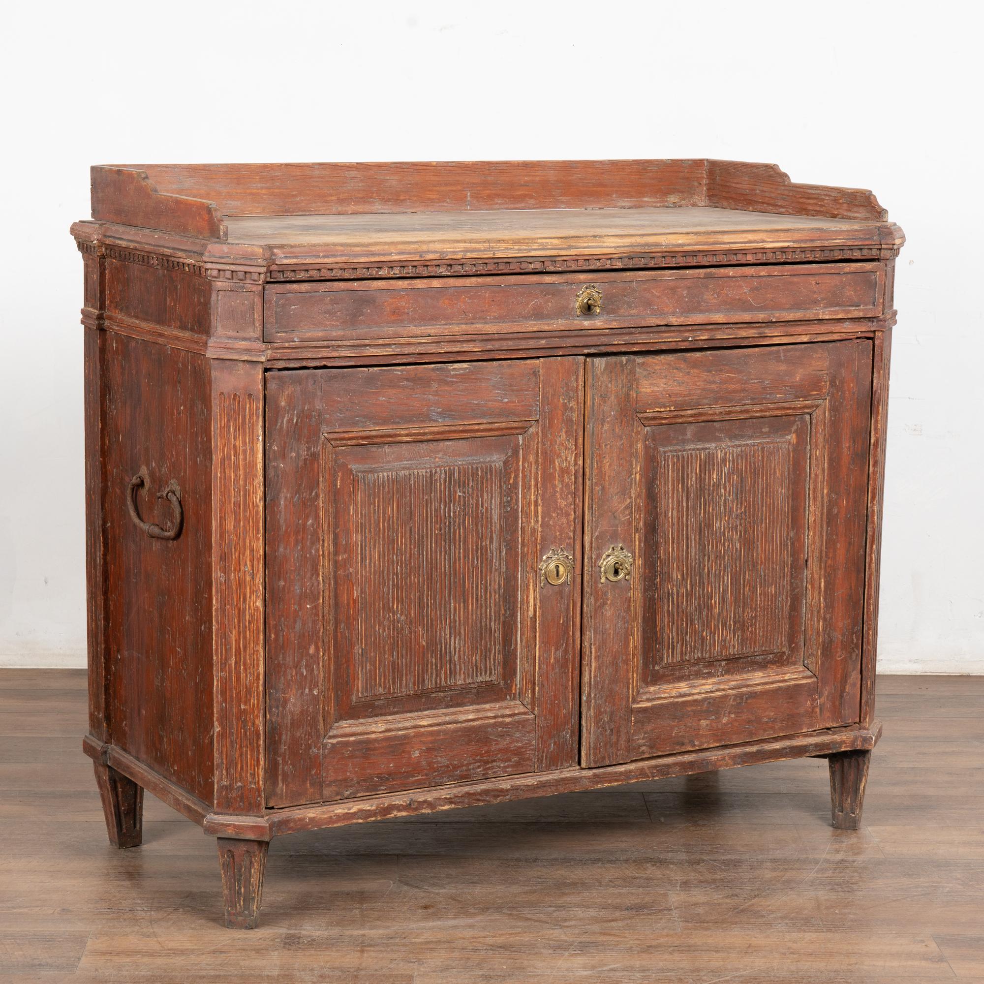 The original brick red painted finish has been lightly scraped bringing out the warm patina of the pine in this lovely Gustavian sideboard or buffet from the Swedish countryside.
One long drawer (with 2 interior dividers on each end) over 2 cabinet
