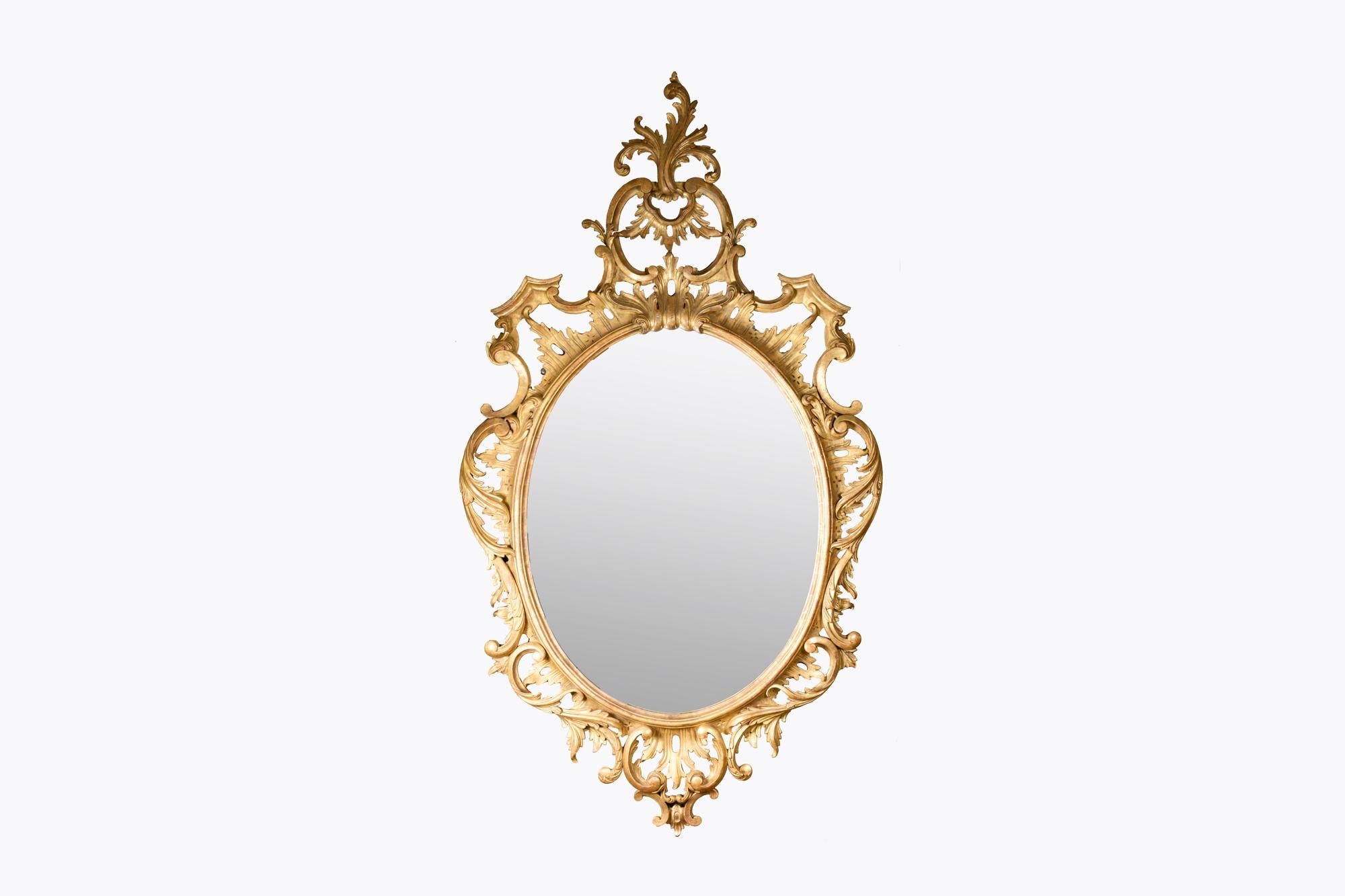 Specchio ovale in legno dorato dell'inizio del XIX secolo in stile rococò con decorazione a volute a C rovesciata e vetro originale
