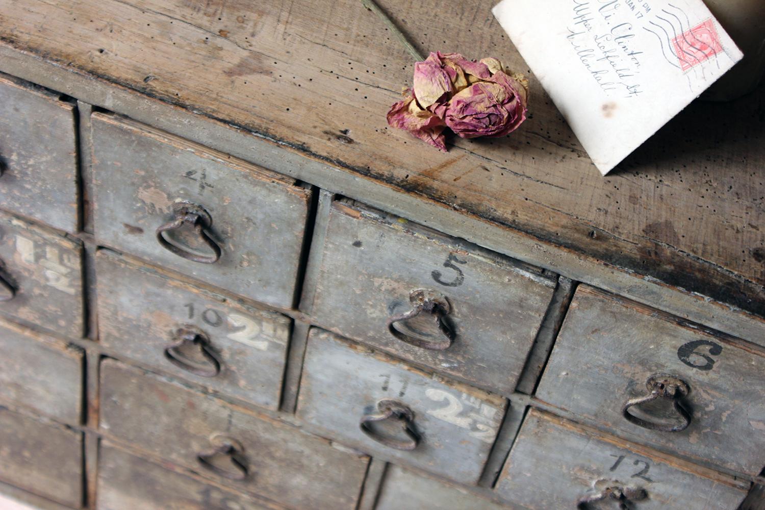 In very original condition, the duck egg Georgian painted flight or bank of twenty drawers each with the original two-pin handles, sign-written numbering and remnants of hand-written workshop labels, and period pencil annotations to one flank,
