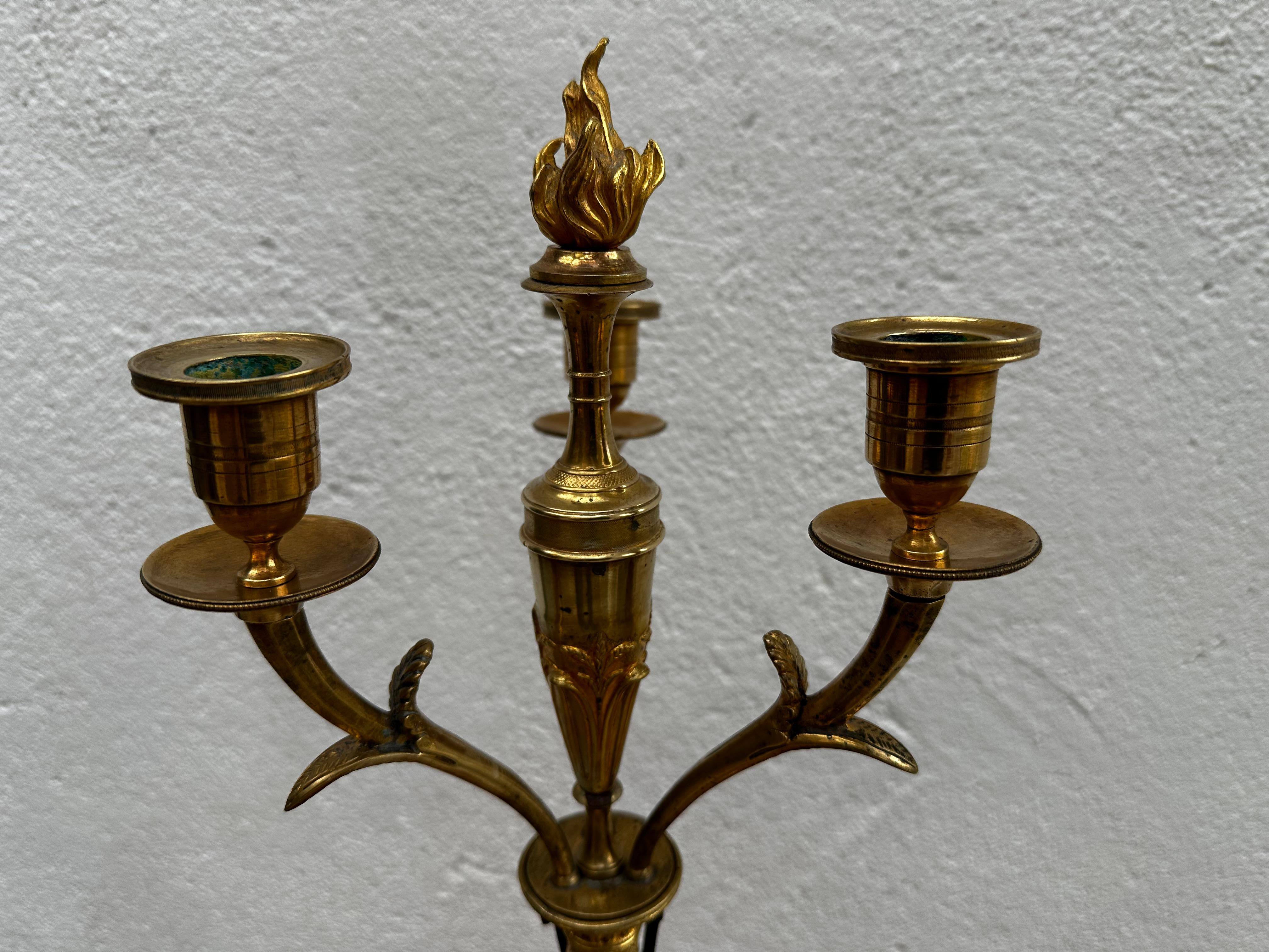 Kandelaber mit Platz für drei Kerzen, hergestellt in Berlin um 1810. Vergoldete und patinierte Bronze. Dekoriert mit einem stehenden Greif mit Frauengesicht, vergoldeten Verzierungen und Löwenfüßen im unteren Teil.
