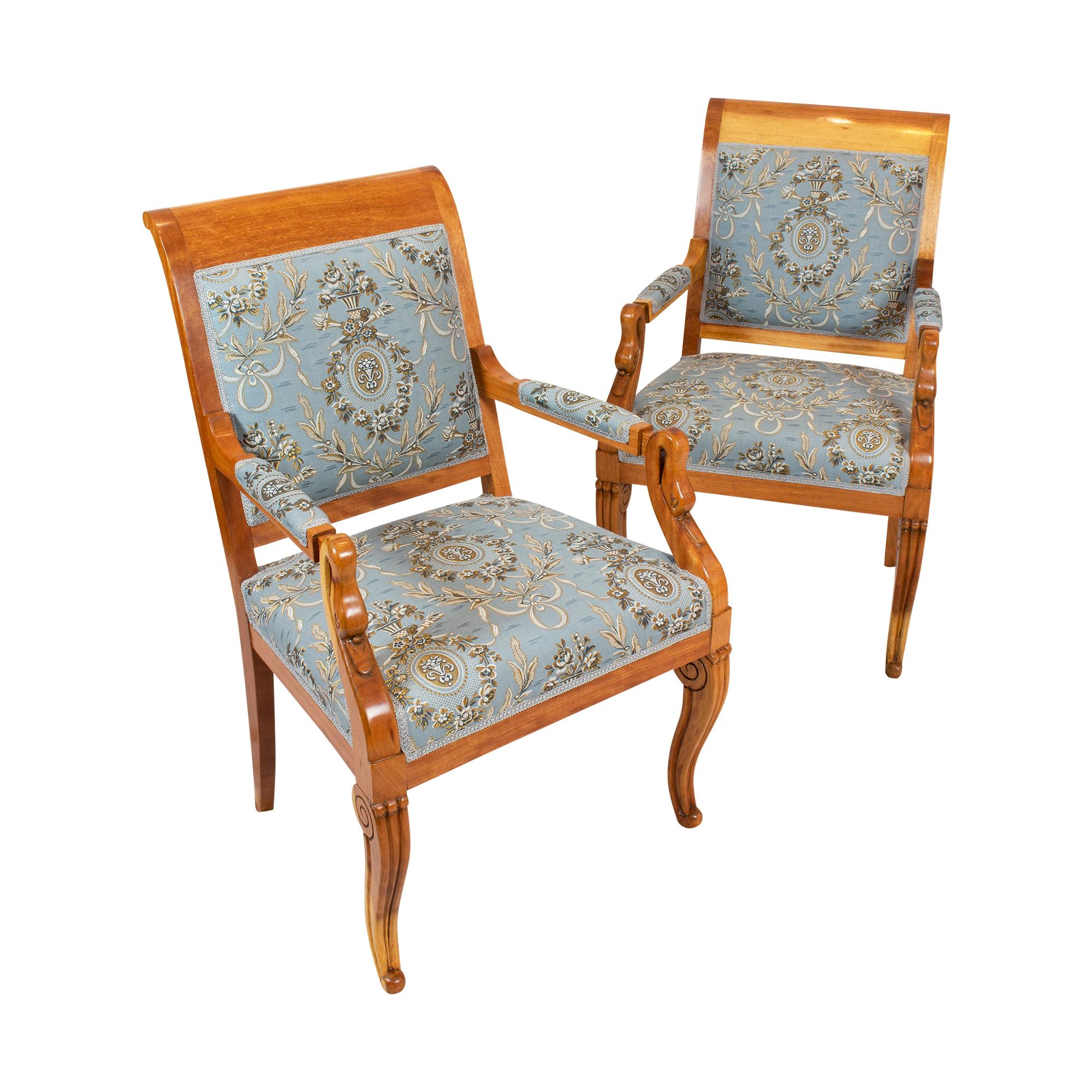A pair of Empire / Biedermeier plum wood from circa 1815, newly upholstered with new fabric in classicist style. The armrests, backrest and seat are upholstered. The upholstery fabric is with gold threads so that the optic is dreamlike. The armrests
