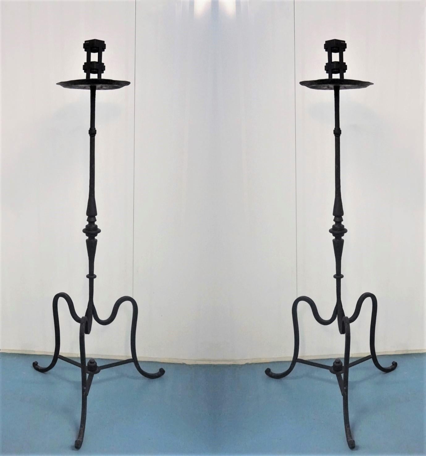 Great pair of Italian Renaissance Revival wrought iron church torchères raised on a large tripod base, early 19th-century. The candleholders are finely handcrafted with elegant detailing and are black painted. Both pieces are in good condition, with