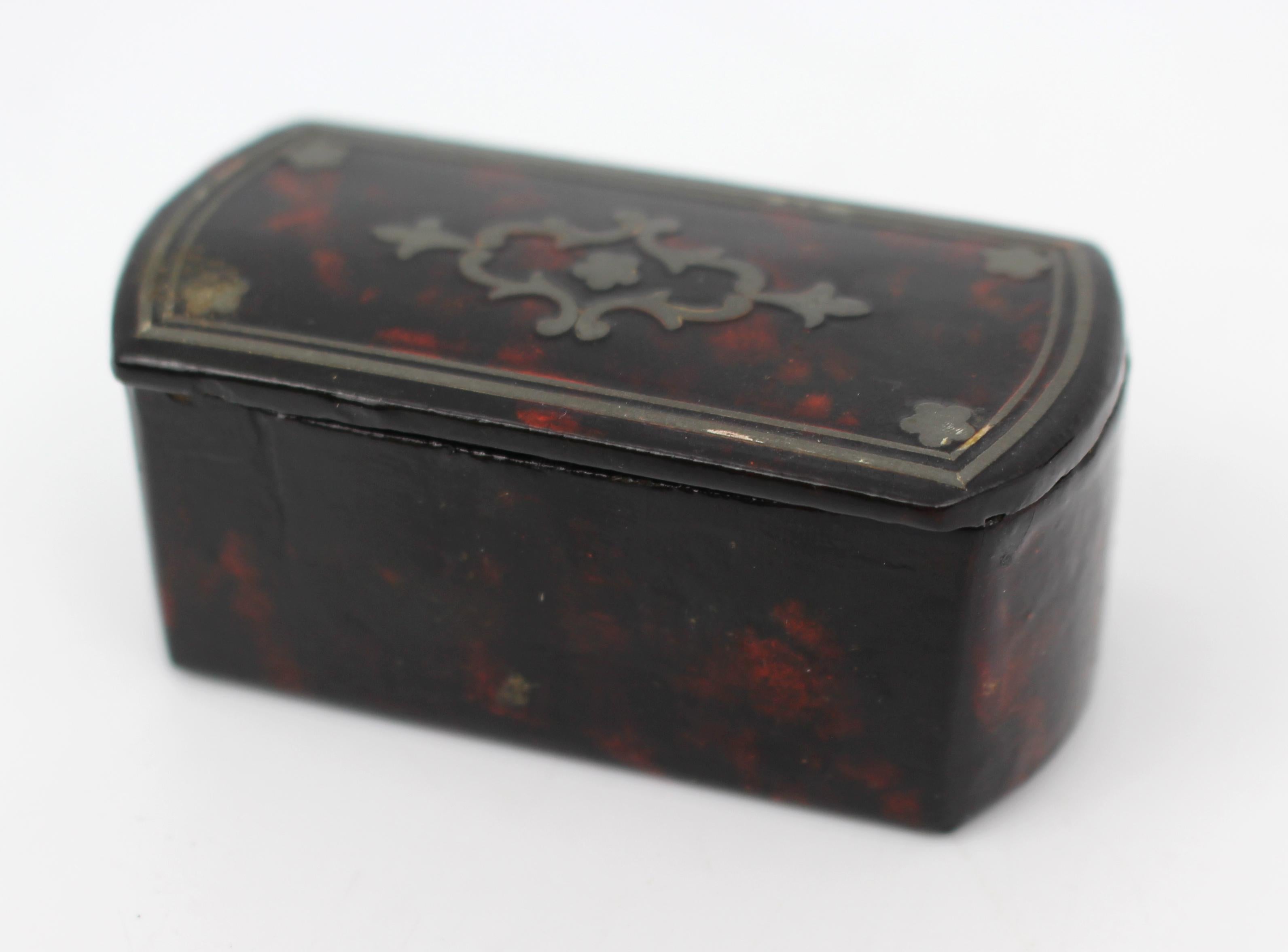 Tabatière en papier mâché du début du XIXe siècle avec incrustation d'argent, c.1820

Petite tabatière décorative du début du XIXe siècle en papier mâché laqué, dont le couvercle en forme est finement incrusté de rinceaux d'argent et de motifs