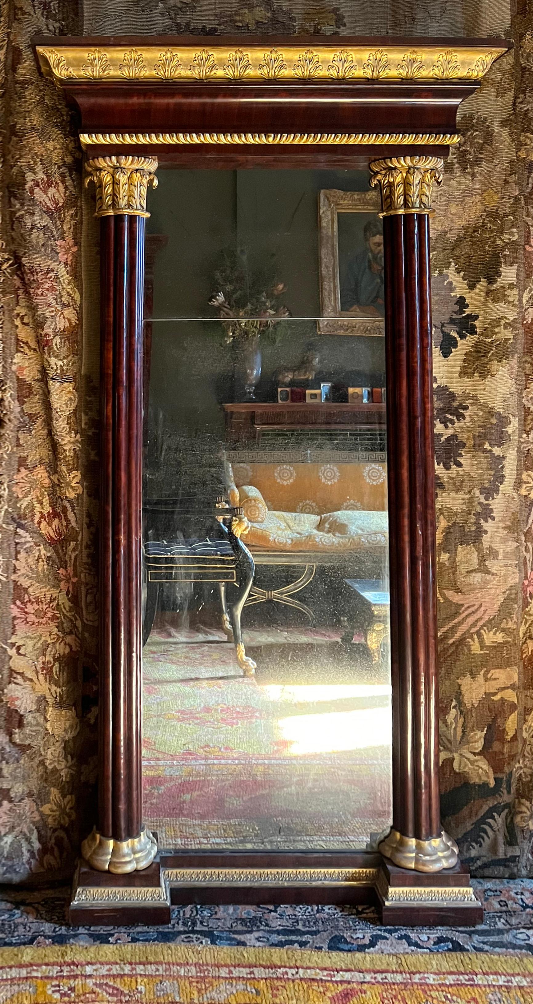 A magnificent architectural neoclassical pier mirror of fine detailing and original finishes. A broad entablature with a dramatic gilded cavetto moulding covered in low relief acanthus leaves rises above a a cove mahogany veneered moulding below