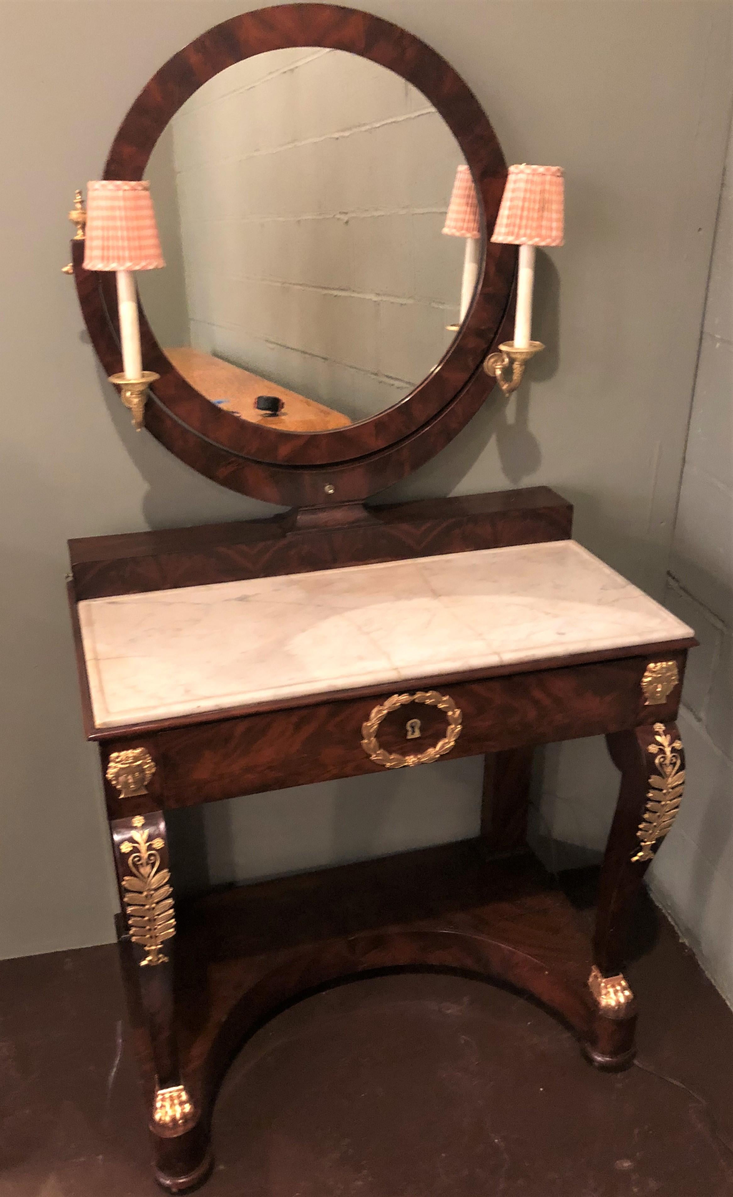 A period Empire vanity desk with mirror and sconces. A fully refinished bronze mounted vanity desk in a fine crotch mahogany having doré bronze mounts and lighted sconces. 

SXX.