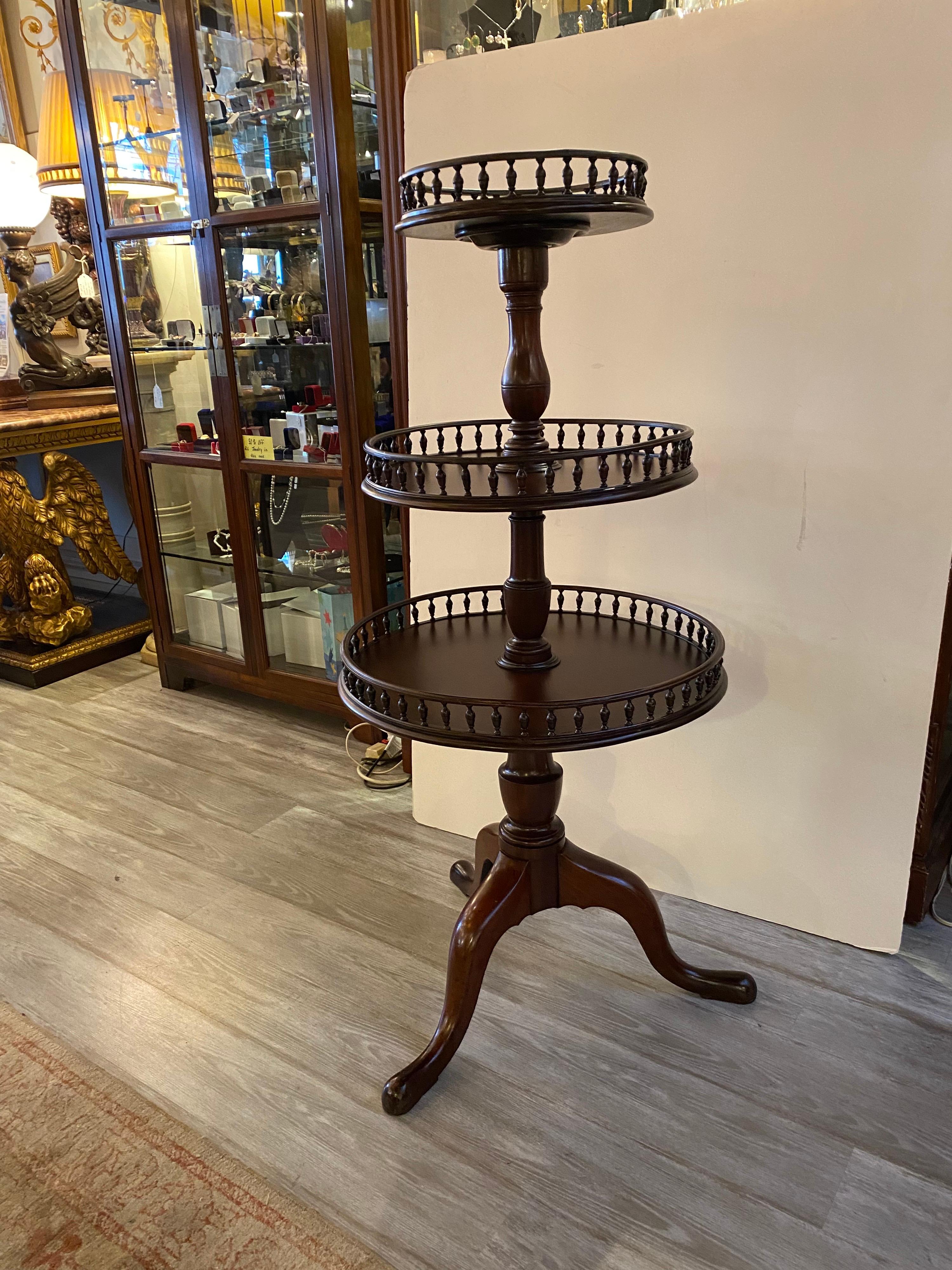 Antique Circa 1800-1820 solid mahogany three tiered dumb water table. The round tops with hand carved urn form rungs along the gallery edges on all tiers. The piece rests on three gently curved legs. The center column that screws together with an